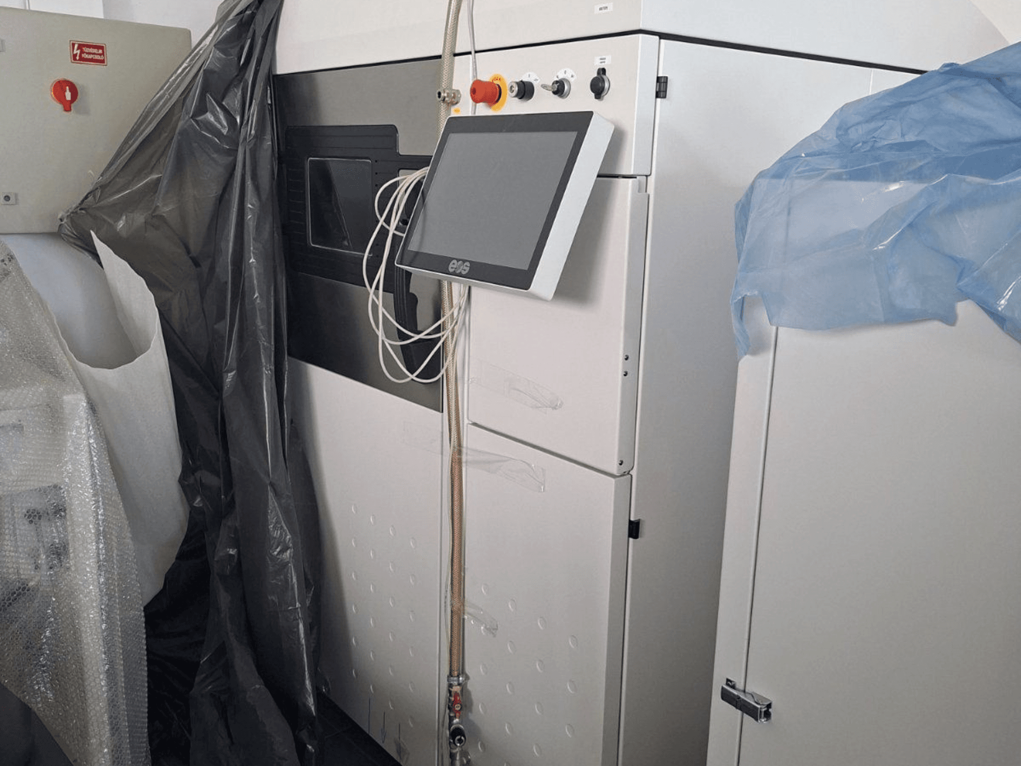 Vista frontal de la impresora 3D metálica EOS M 290, con pantalla táctil, panel de control y cubiertas protectoras.