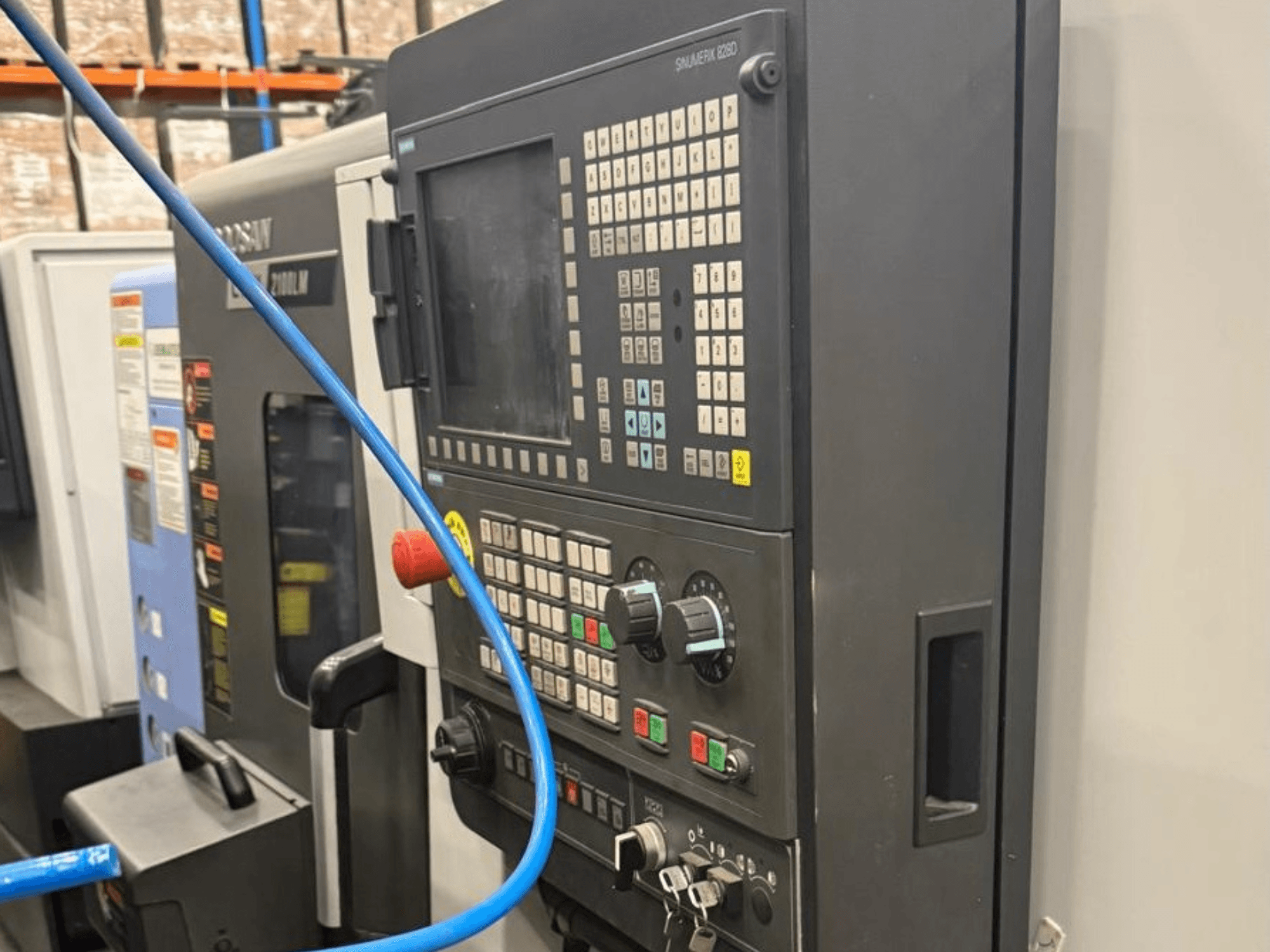 Panel de control de una herramienta de mecanizado, vista frontal, con botones, mandos y una pantalla digital para un funcionamiento preciso.