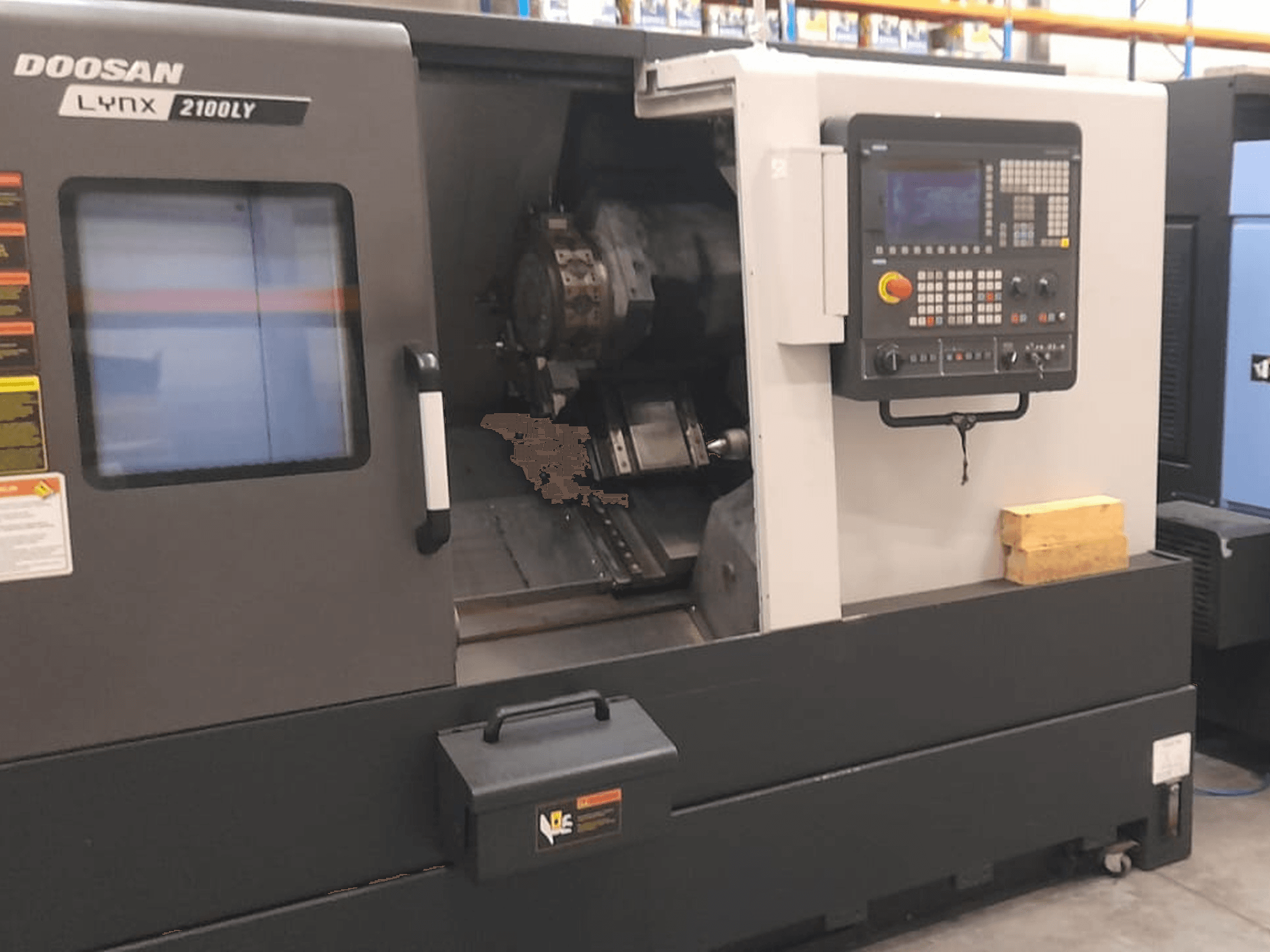 Torno CNC Doosan Lynx 2100LY, vista frontal que muestra el panel de control, el portaherramientas y el espacio de trabajo interior; etiquetas técnicas visibles.