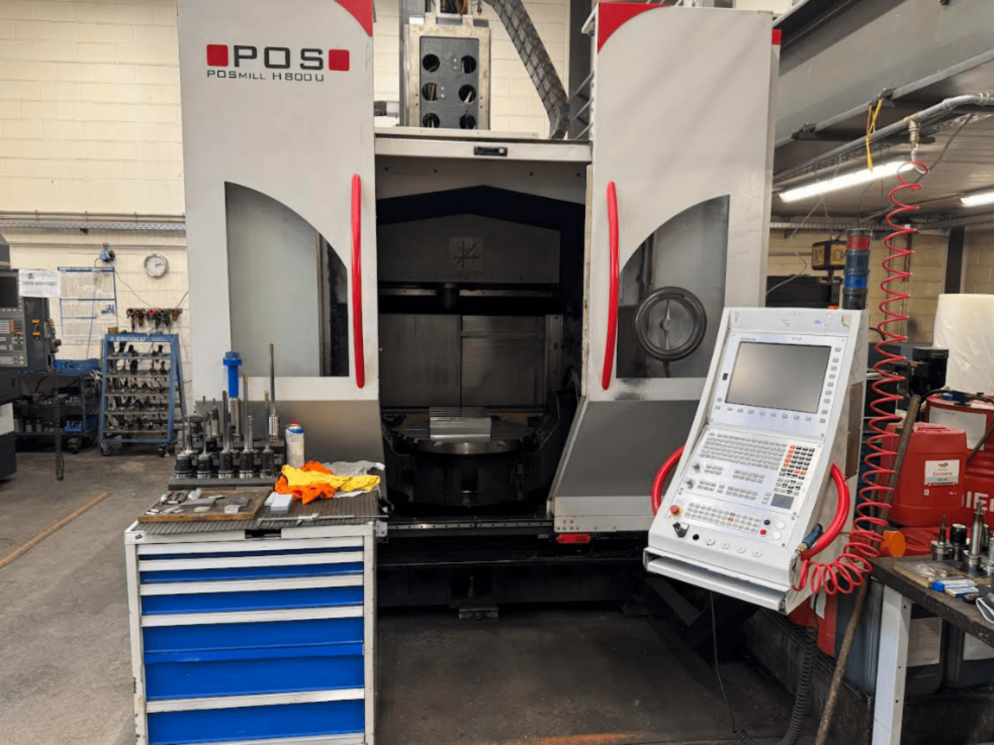 Máquina CNC POSMILL H800 U vista de frente, mostrando el panel de control y la zona de trabajo con herramientas y equipos cercanos.