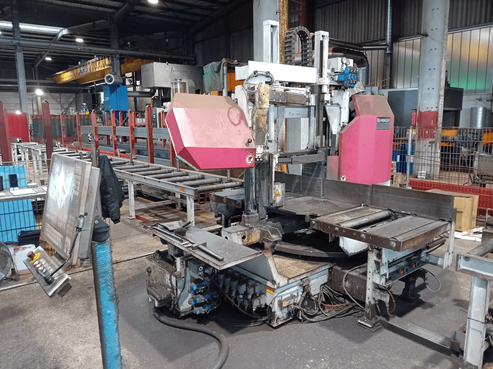 Sierra de cinta Behringer en una fábrica, vista frontal, con una gran hoja de corte y panel de control con botones.