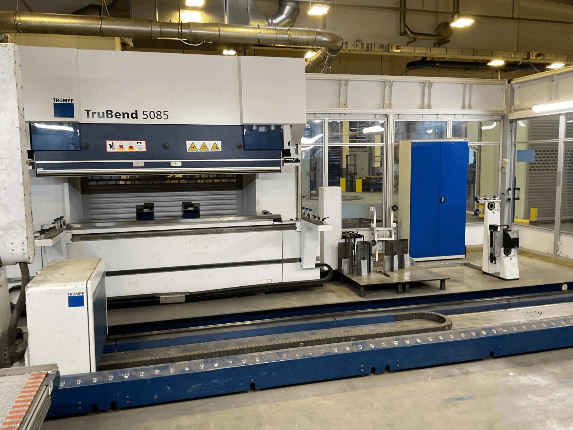 TruBend 5085 de TRUMPF, vista lateral de una gran plegadora de metal con panel de control y varias herramientas a su lado.