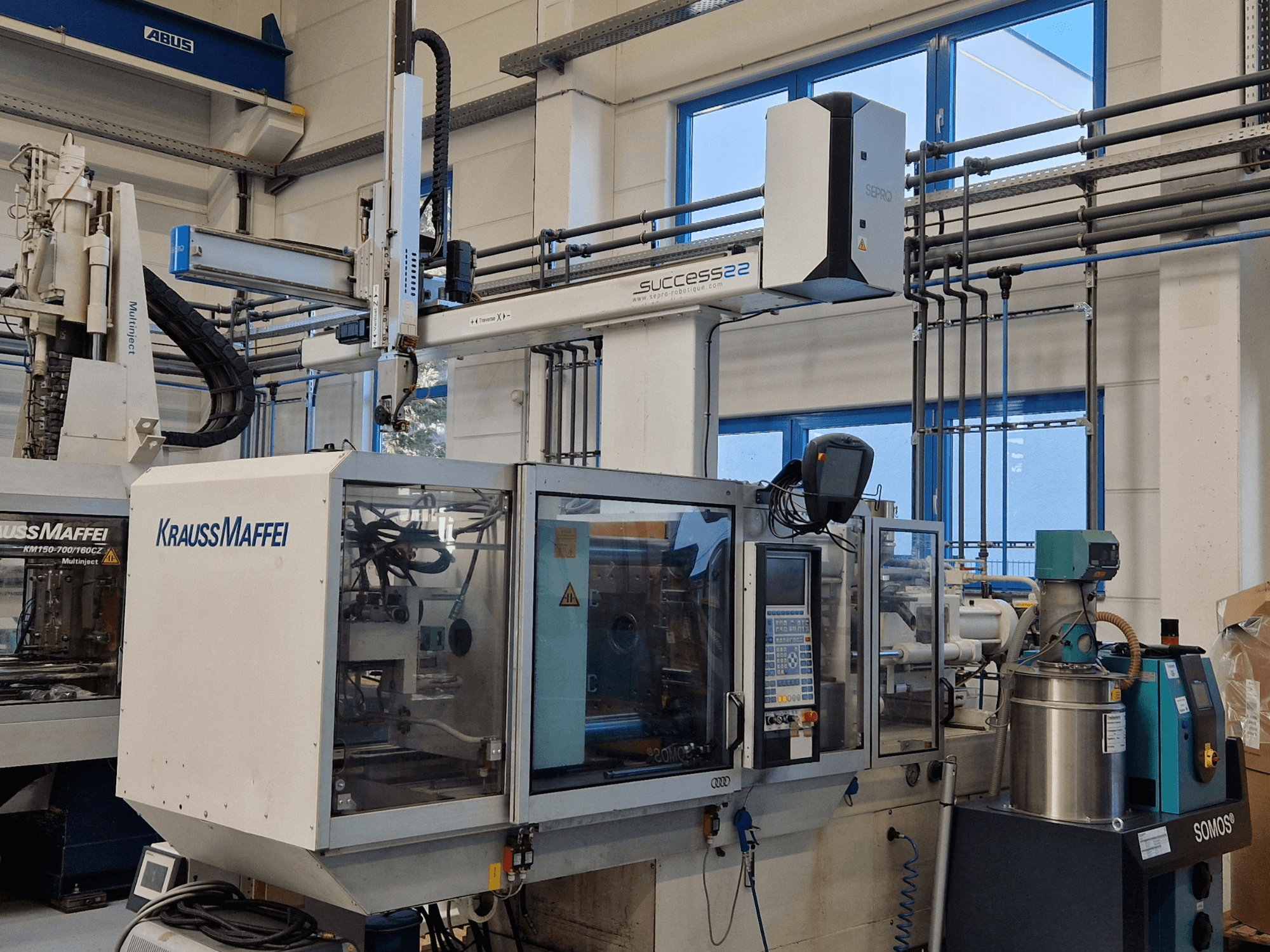 Máquina de moldeo por inyección KraussMaffei Success 22 con panel de control, vista de frente en un entorno de fábrica.