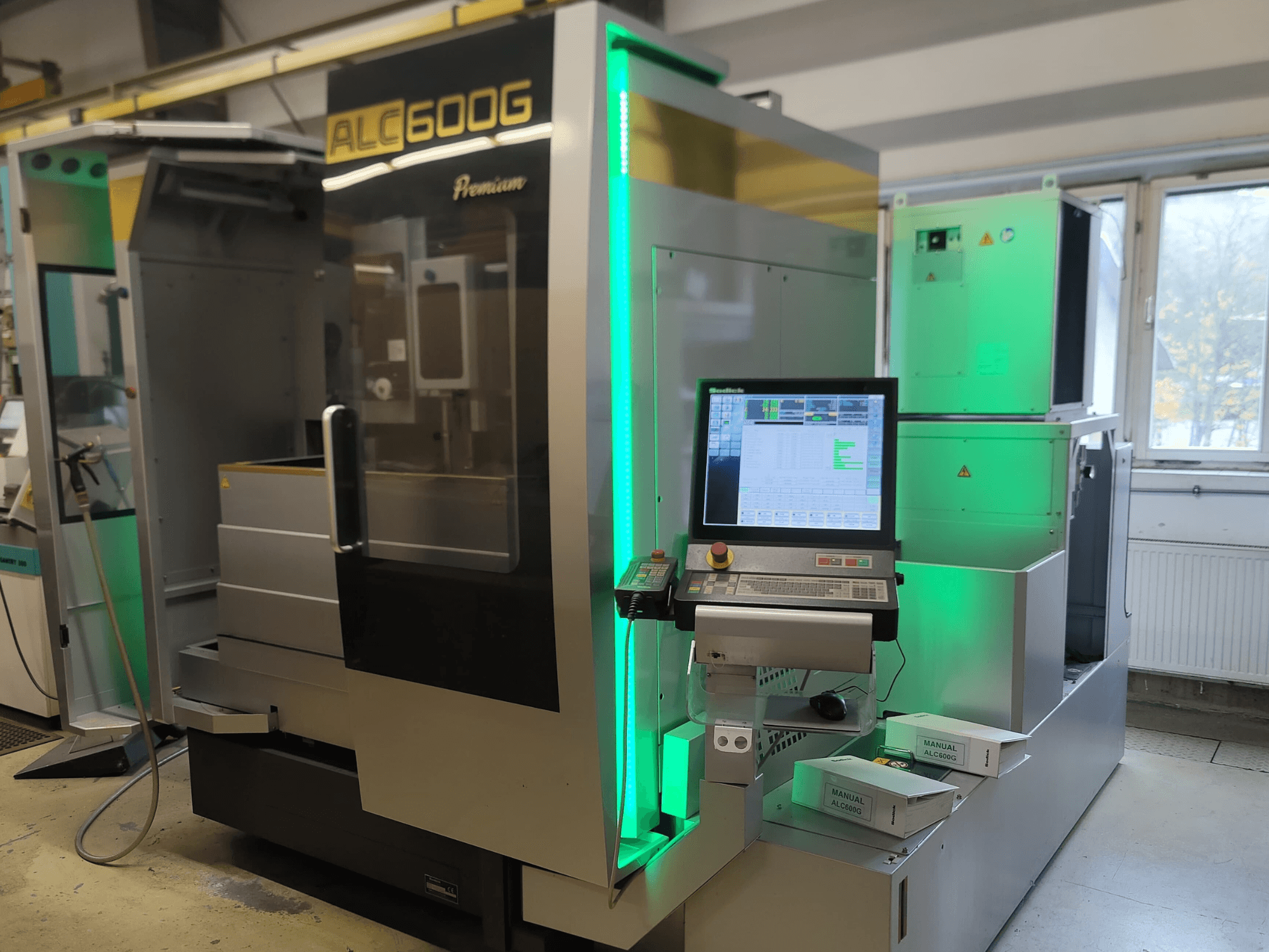 Máquina de electroerosión por hilo Sodick ALC600G Premium, vista frontal, mostrando el panel de control y los detalles exteriores iluminados.