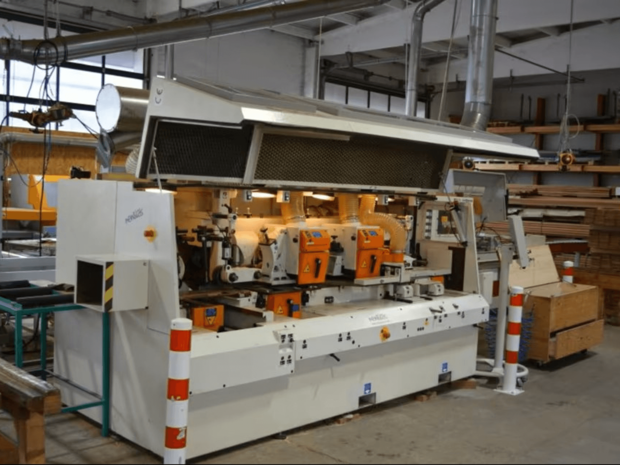 Procesadora de madera PENIGAS, vista frontal, con doble cabezal de corte naranja y sistema de extracción de polvo en un taller.