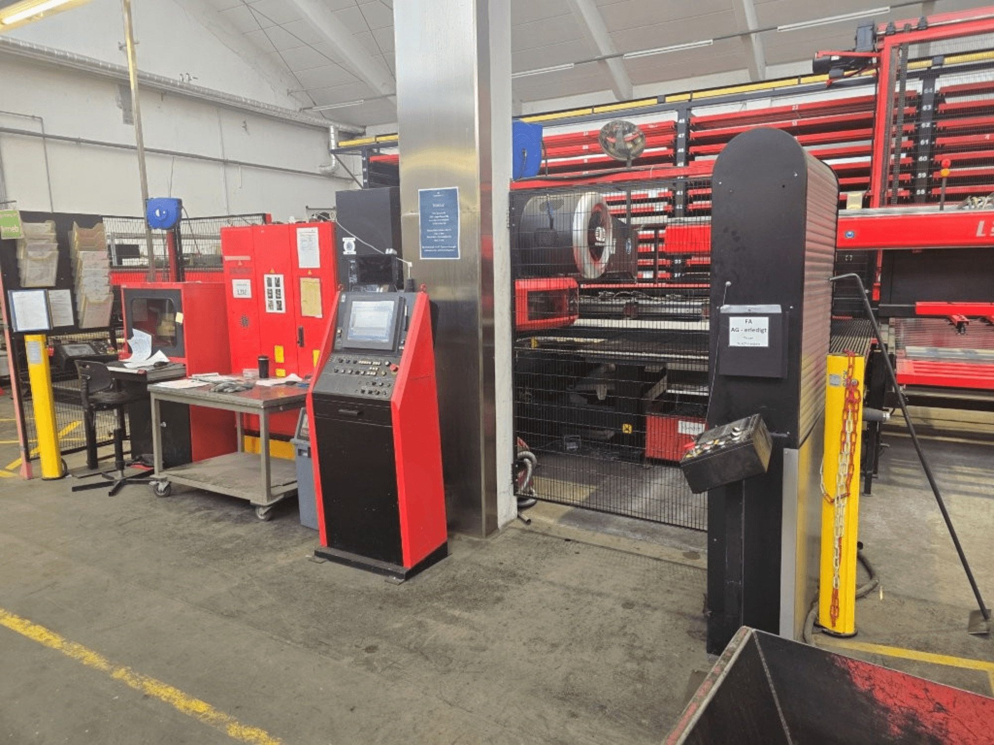 Vista frontal de la punzonadora CNC AMADA EMZ 3610 NT, en la que se aprecian los mandos de control y la cabina de seguridad en un entorno industrial.