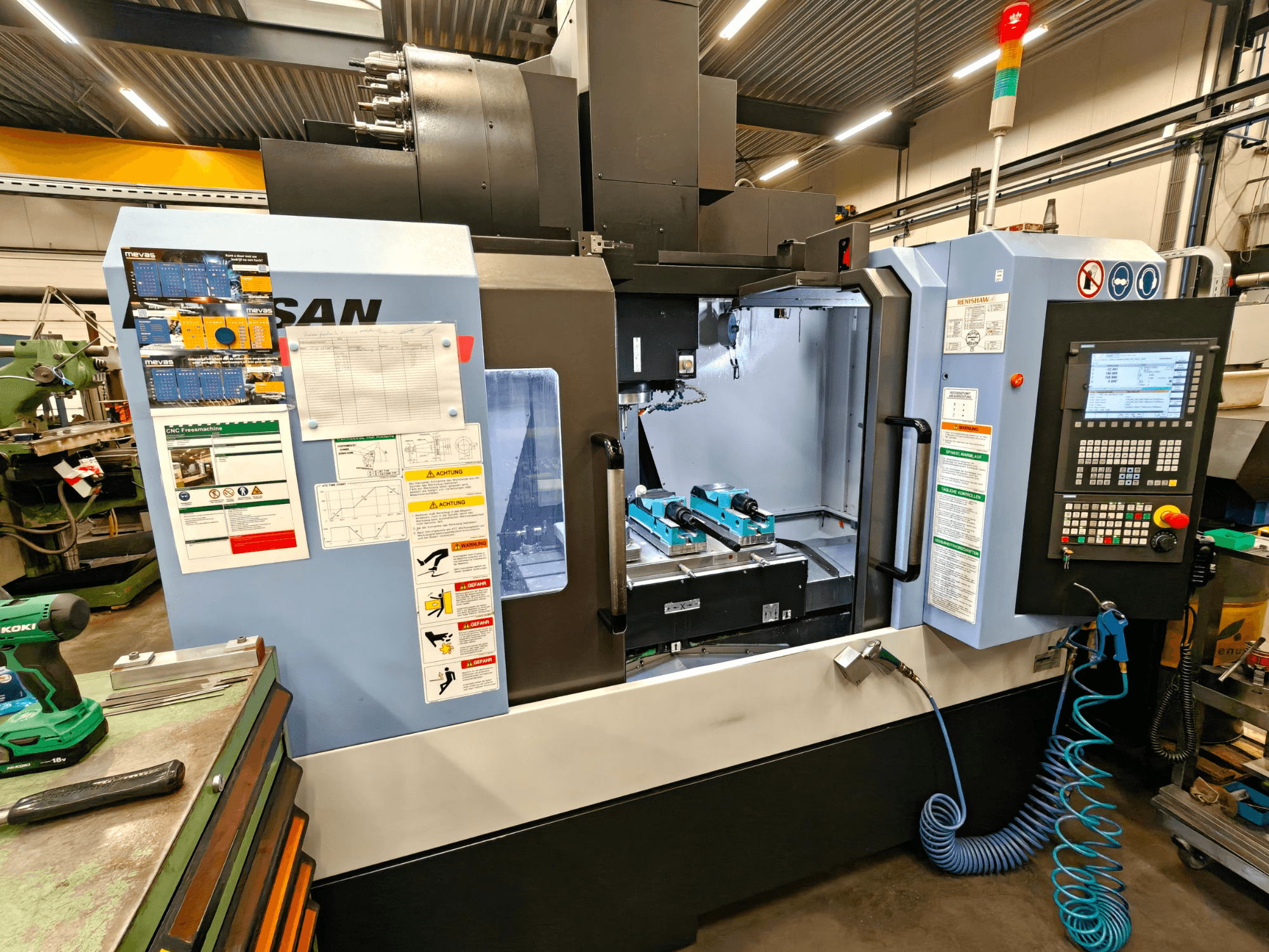 Centro de mecanizado vertical DOOSAN DNM 400 II en un taller, con controles, portaherramientas y señalización de seguridad, vista frontal.