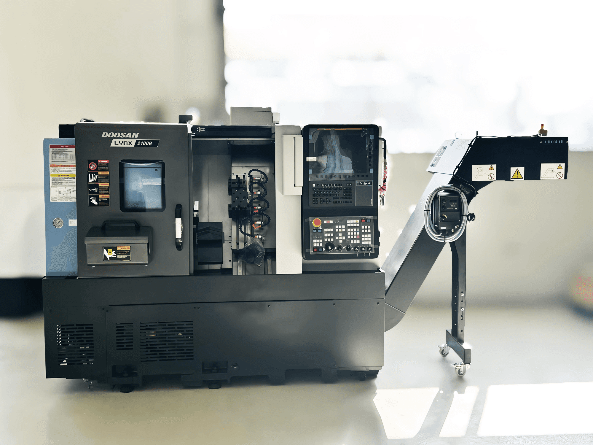 Tornos DOOSAN LYNX 2100GA de tipo suizo en vista lateral con panel de control y portaherramientas visibles.