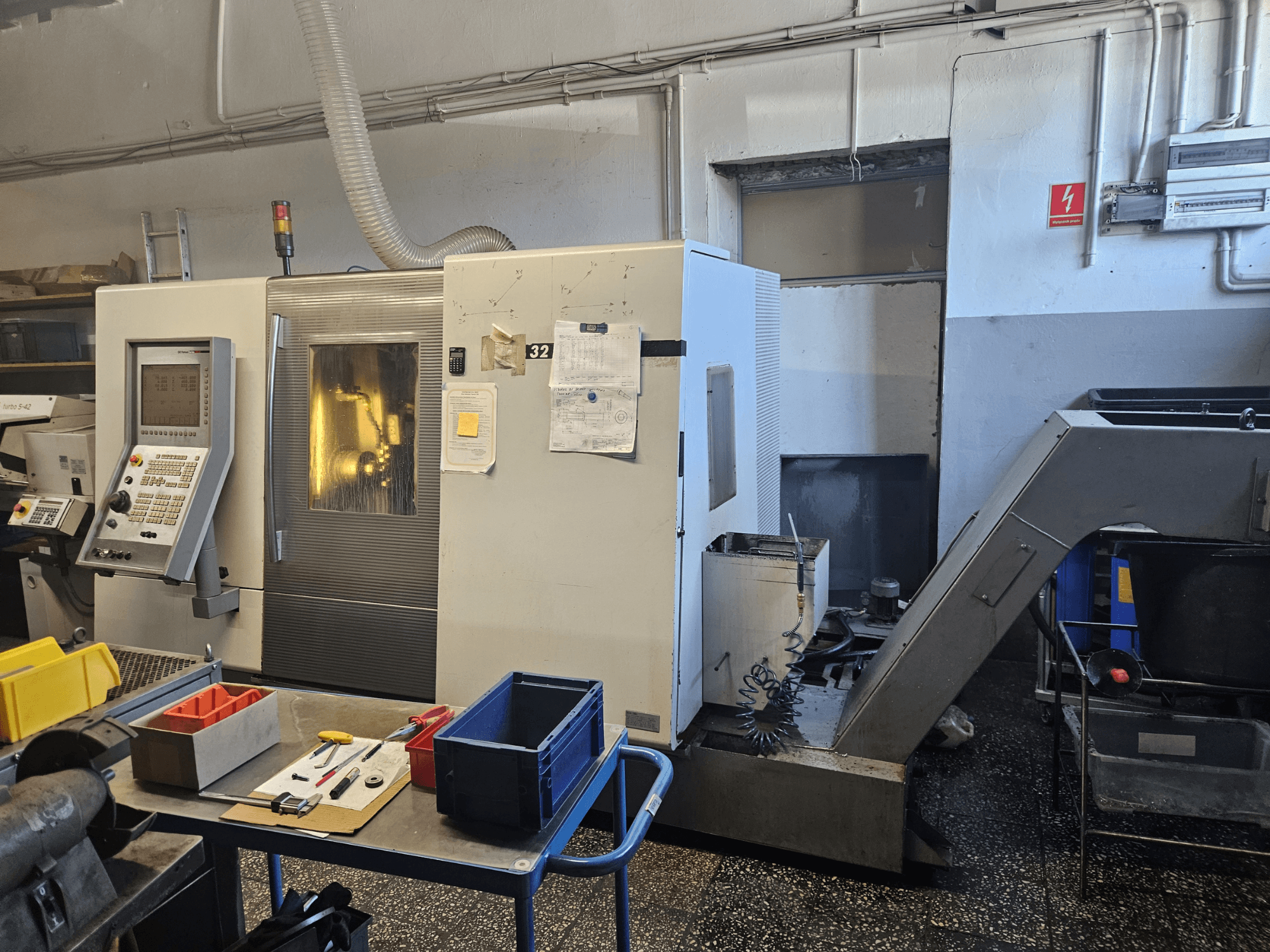 Máquina de torneado multihusillo DMG GILDEMEISTER Sprint 32 linear, vista frontal en un taller, con panel de control y herramientas visibles.