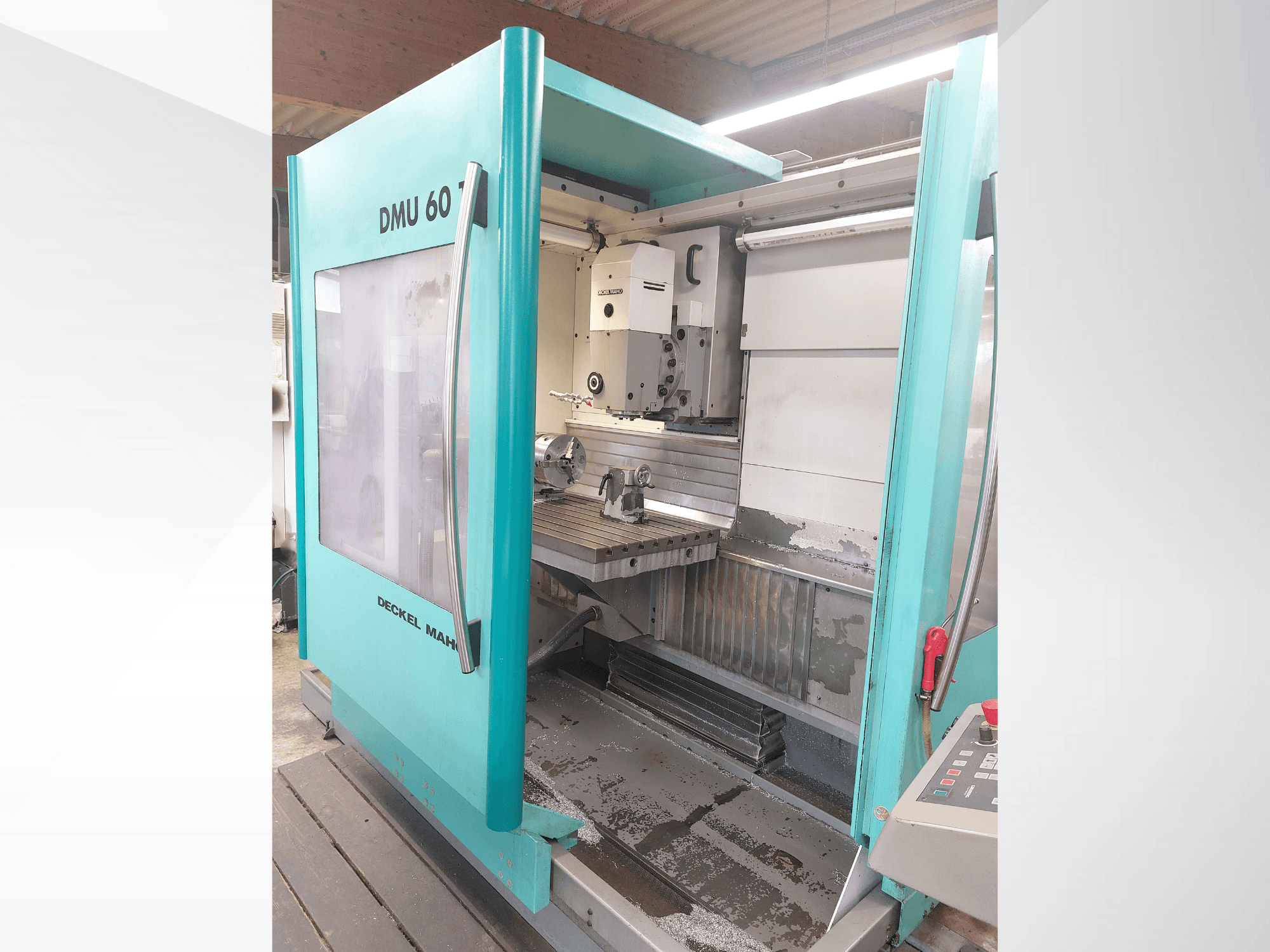 Máquina CNC Deckel MAHO DMU 60, vista frontal. Presenta un panel de control visible y una mesa de fresado con una configuración de pieza de trabajo.