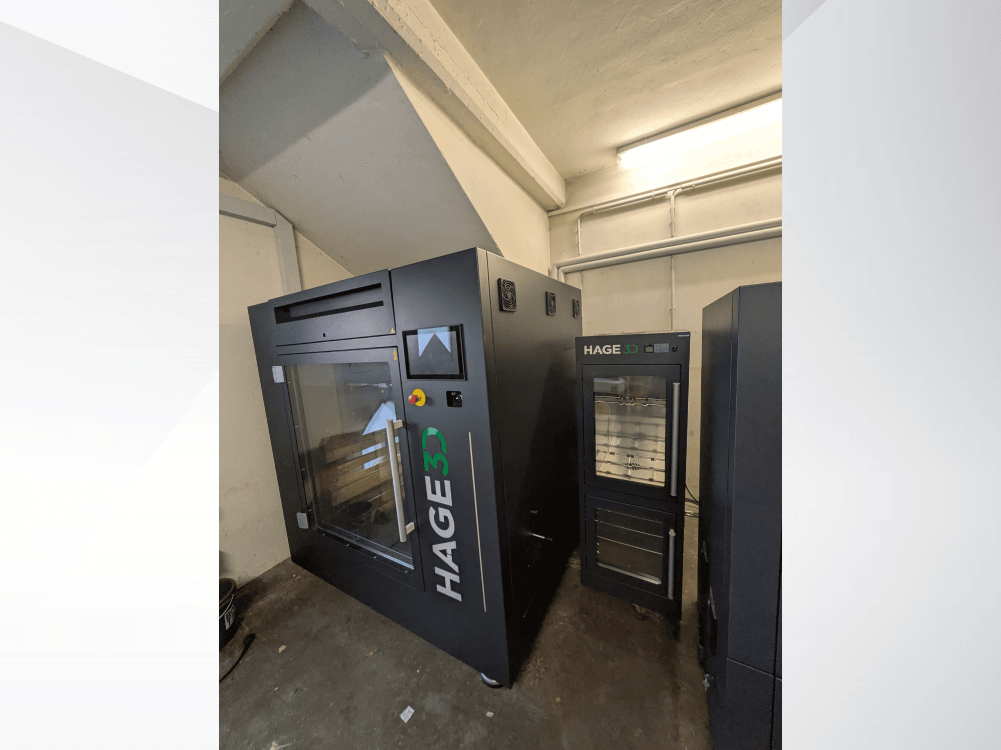 Impresora 3D de plástico HAGE 3D Precision One vista desde un ángulo, con puerta y panel de control transparentes, y espacio de almacenamiento a su lado.