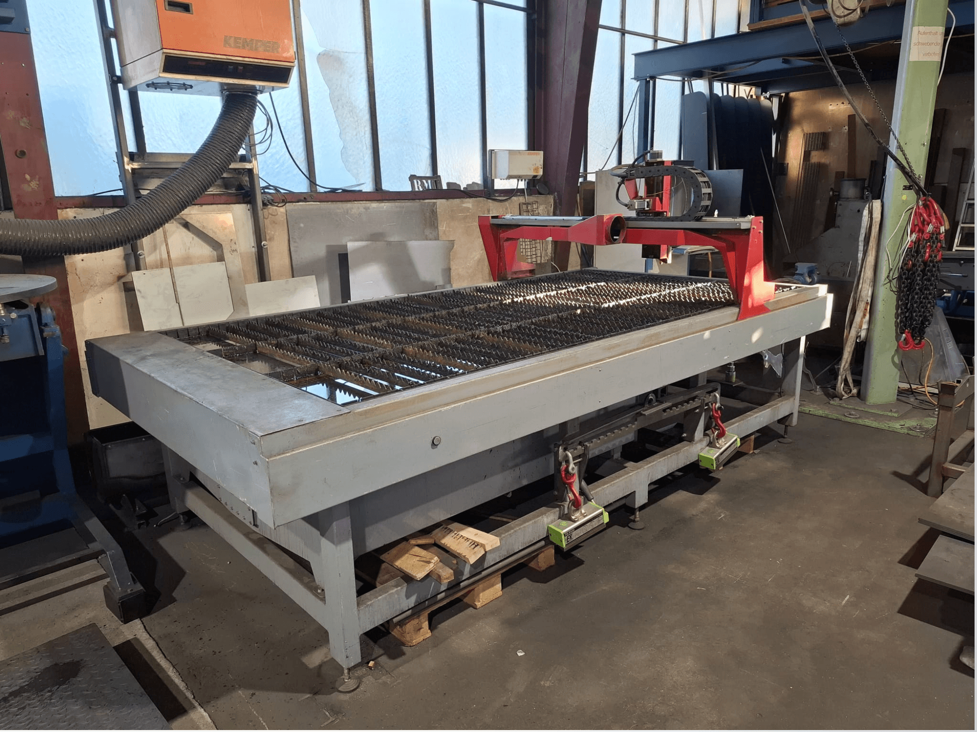 Máquina de corte por plasma PLASMACUT 3015T, vista de perfil, que cuenta con una amplia mesa de corte con listones metálicos y un bastidor rojo.