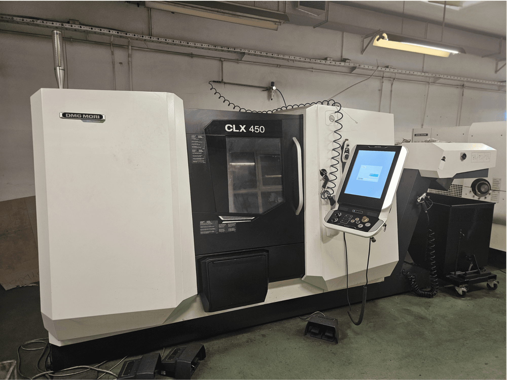 Máquina CNC DMG MORI CLX 450 en vista frontal, con panel de control y pantalla táctil, situada en un entorno de taller.