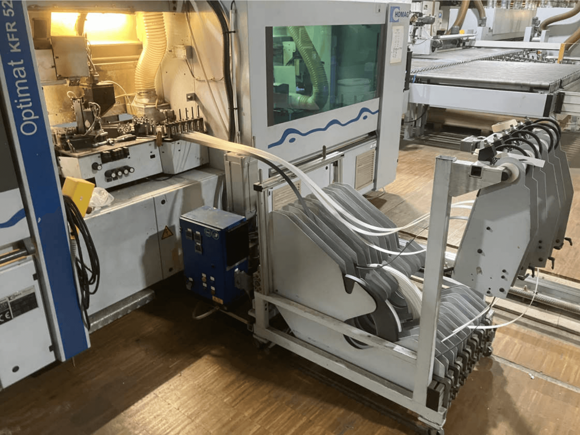 Máquina encintadora de doble cara HOMAG Optimat KFR 526/10/A3/35, vista desde un lateral, en la que se aprecian el panel de control y los rodillos de encintado.