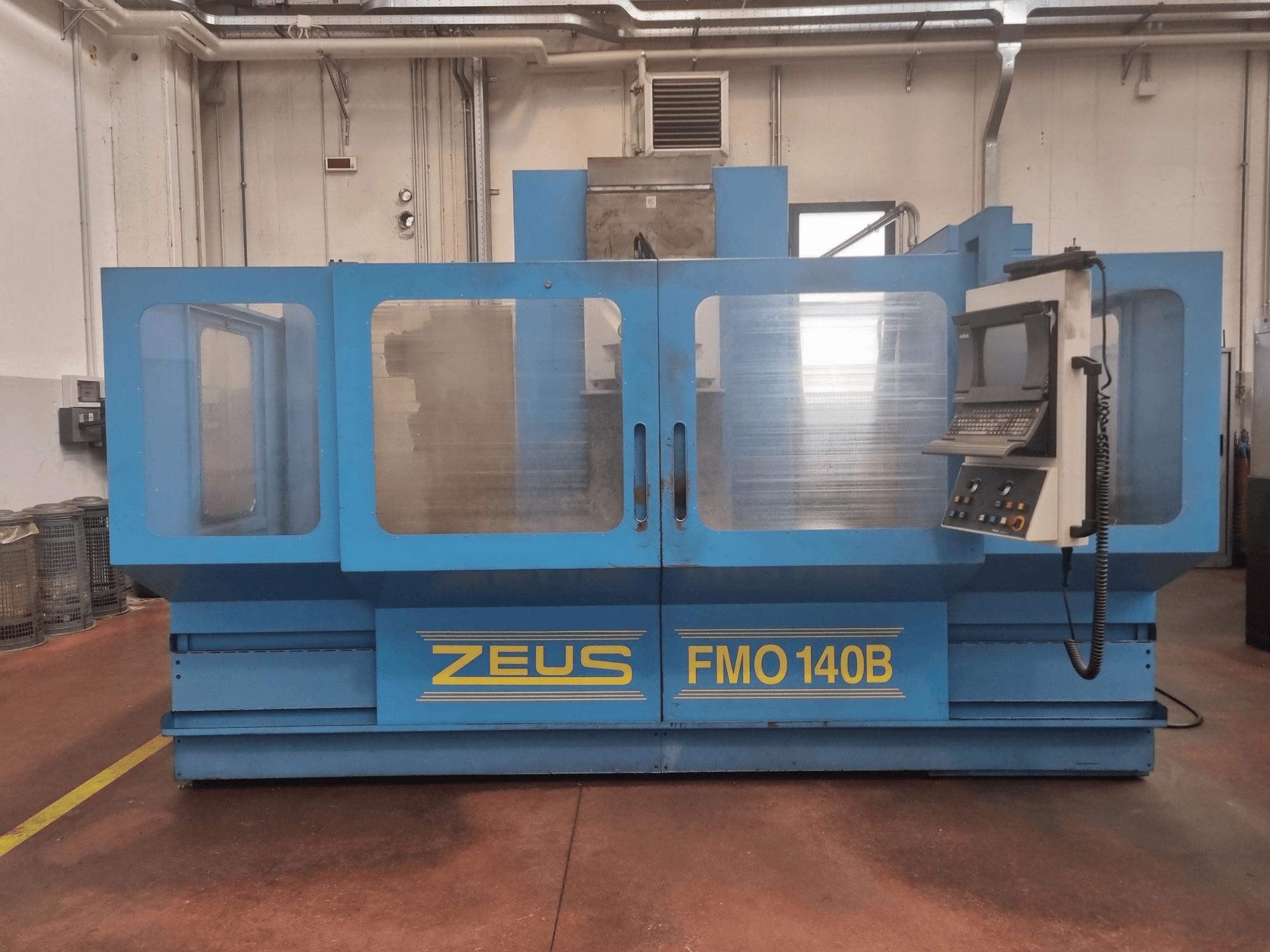 Máquina Zeus FMO 140B en azul, vista frontal; incorpora panel de control y grandes paneles transparentes para mayor visibilidad.