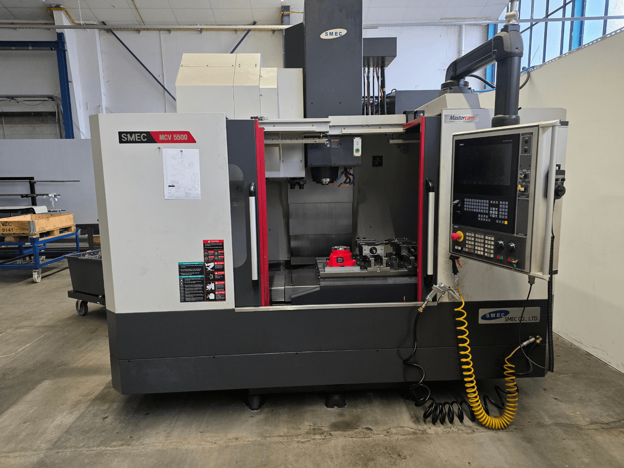 Centro de mecanizado vertical SMEC MCV 5500, vista frontal, en la que se aprecian el panel de control y el interior de la máquina con las herramientas.