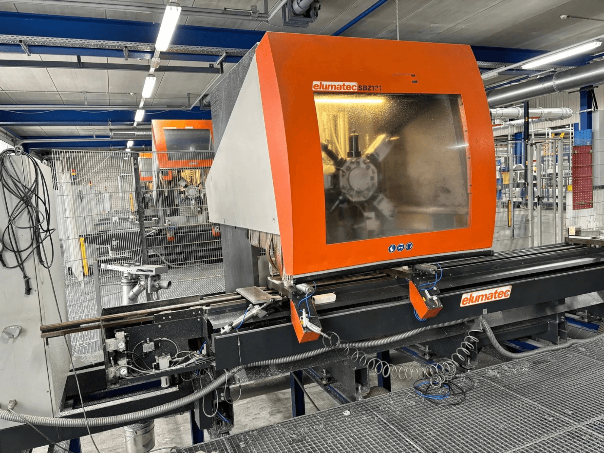 Centro de mecanizado vertical Elumatec SBZ 131, vista frontal, mostrando el panel de control, los detalles de la maquinaria y el entorno de trabajo circundante.