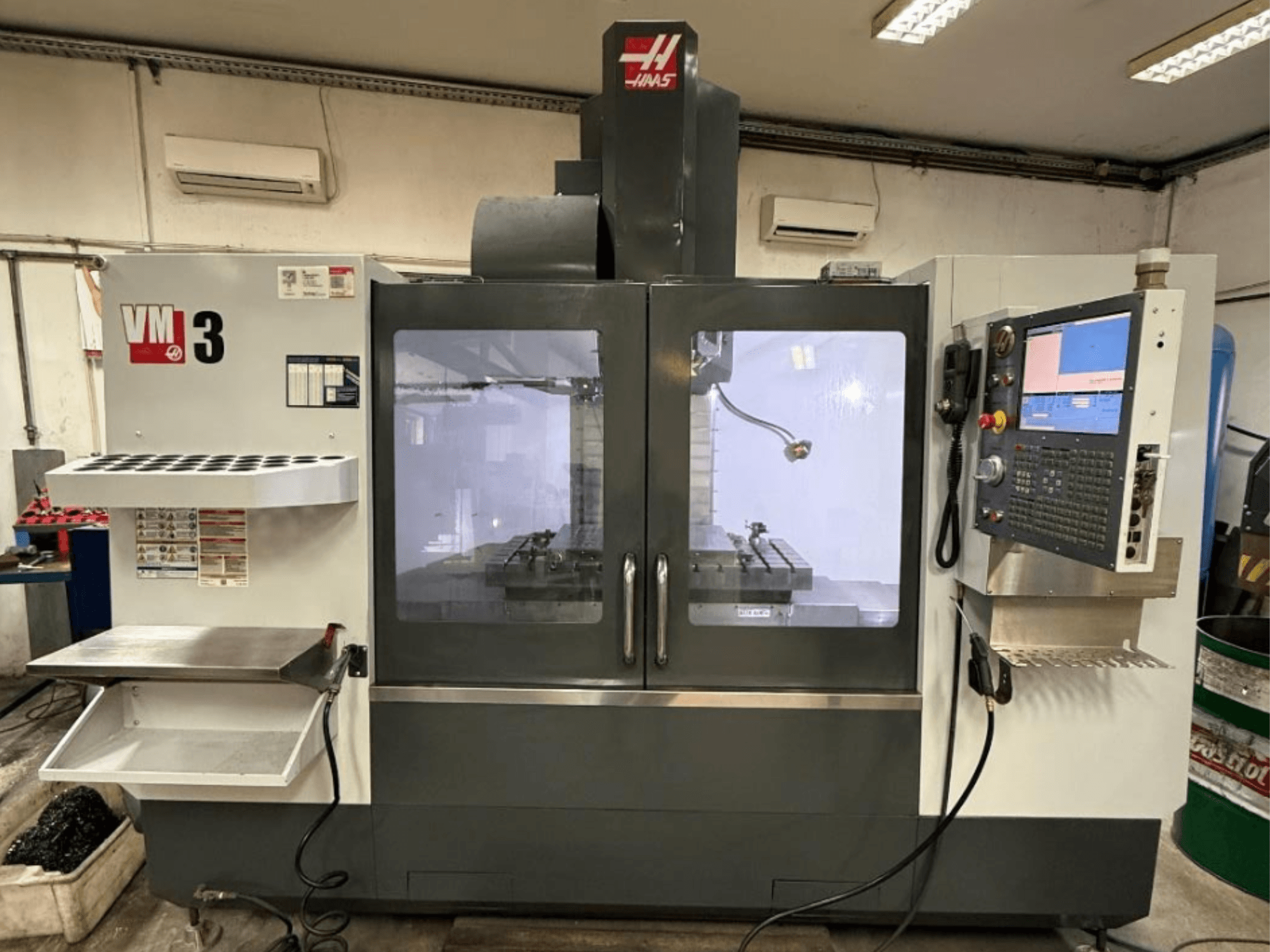 Centro de mecanizado vertical Haas VM-3 visto de frente, con un amplio panel de control y un área de trabajo visible con herramientas.