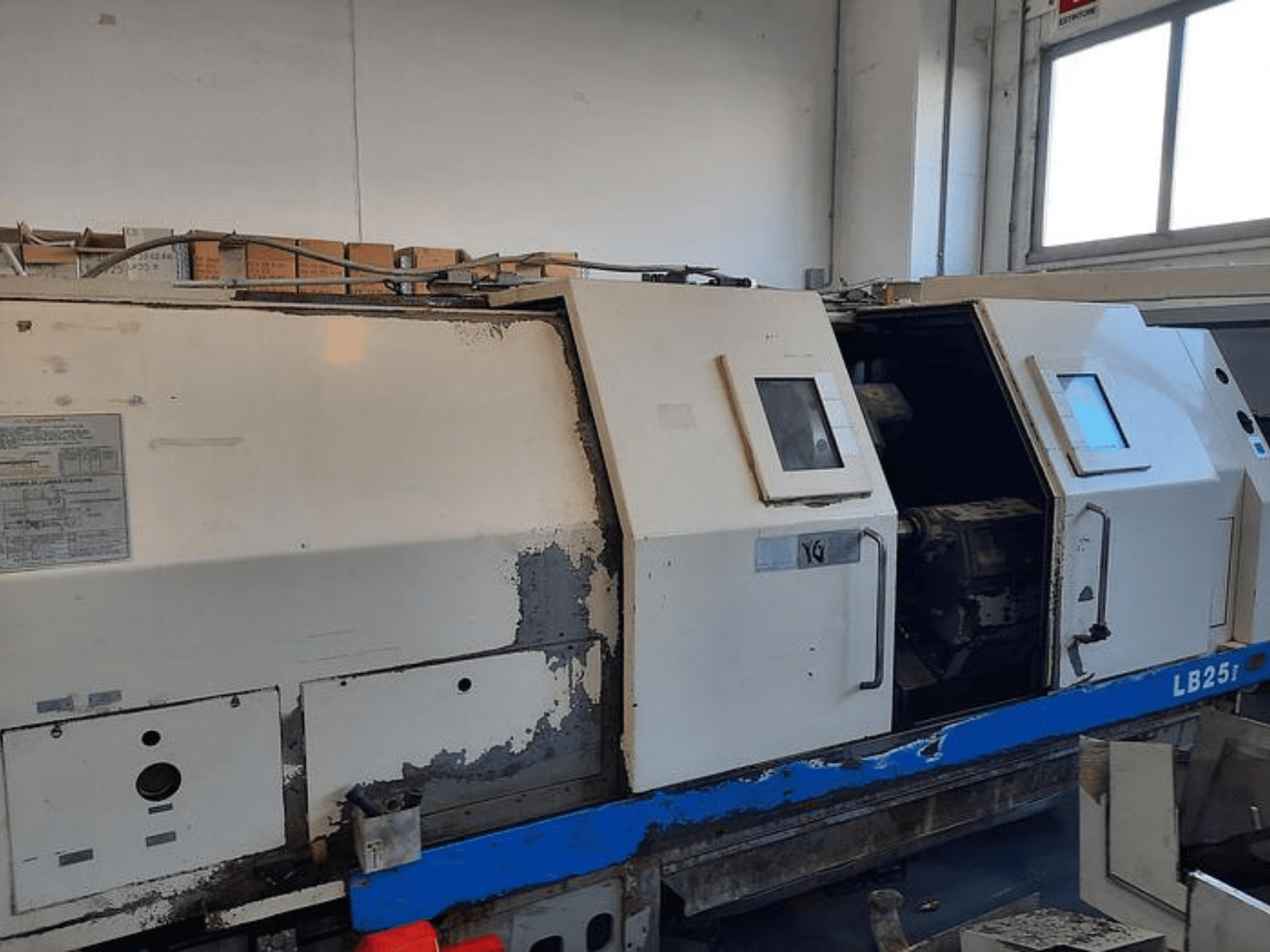 Máquina de torno LB251 usada, vista lateral que muestra el exterior desgastado, panel abierto que revela el mecanismo interior y los controles de funcionamiento.