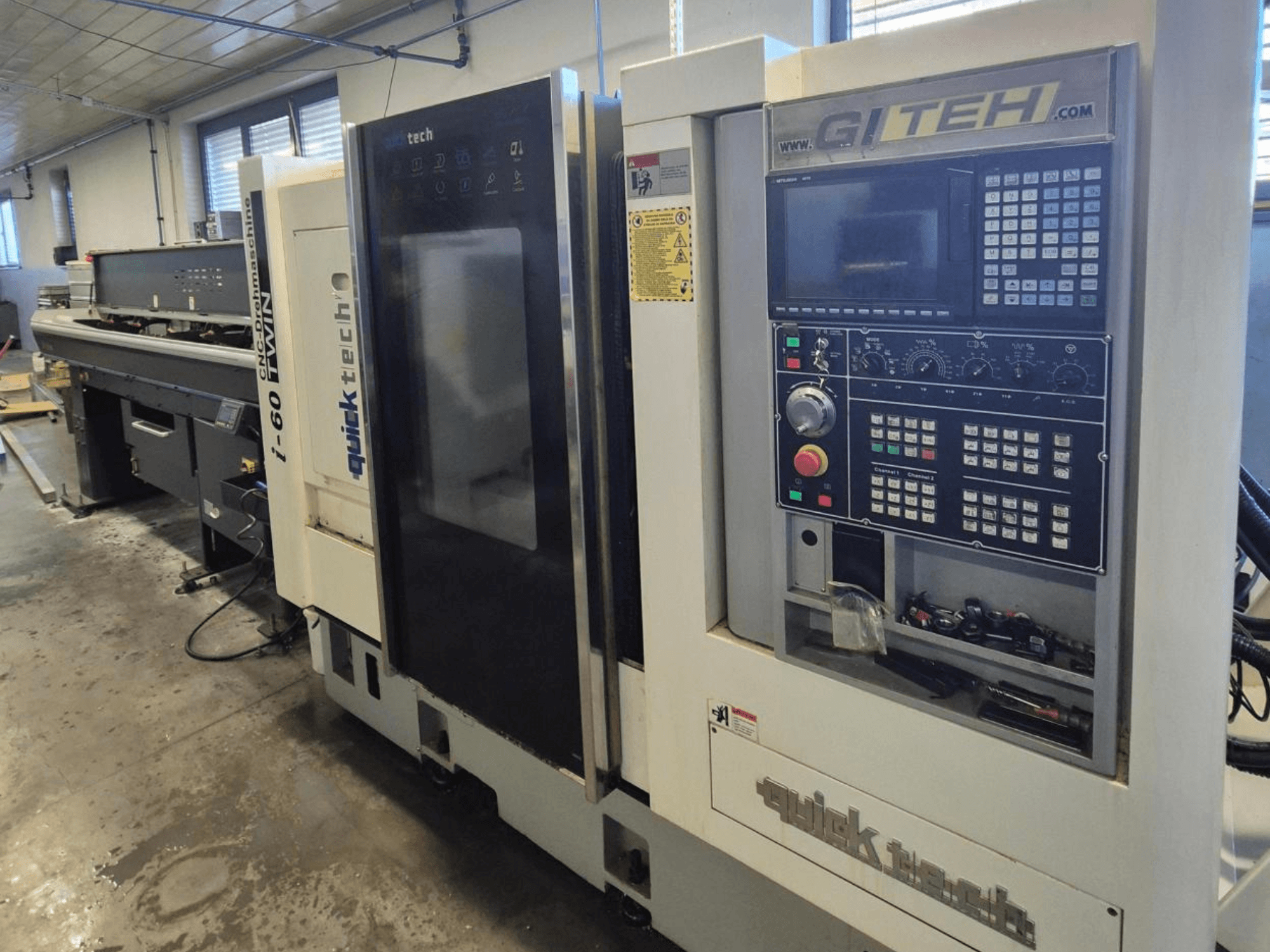Máquina CNC doble Quick Tech i-60, vista frontal, con panel de control GITEH y botones operativos, en un entorno de taller.