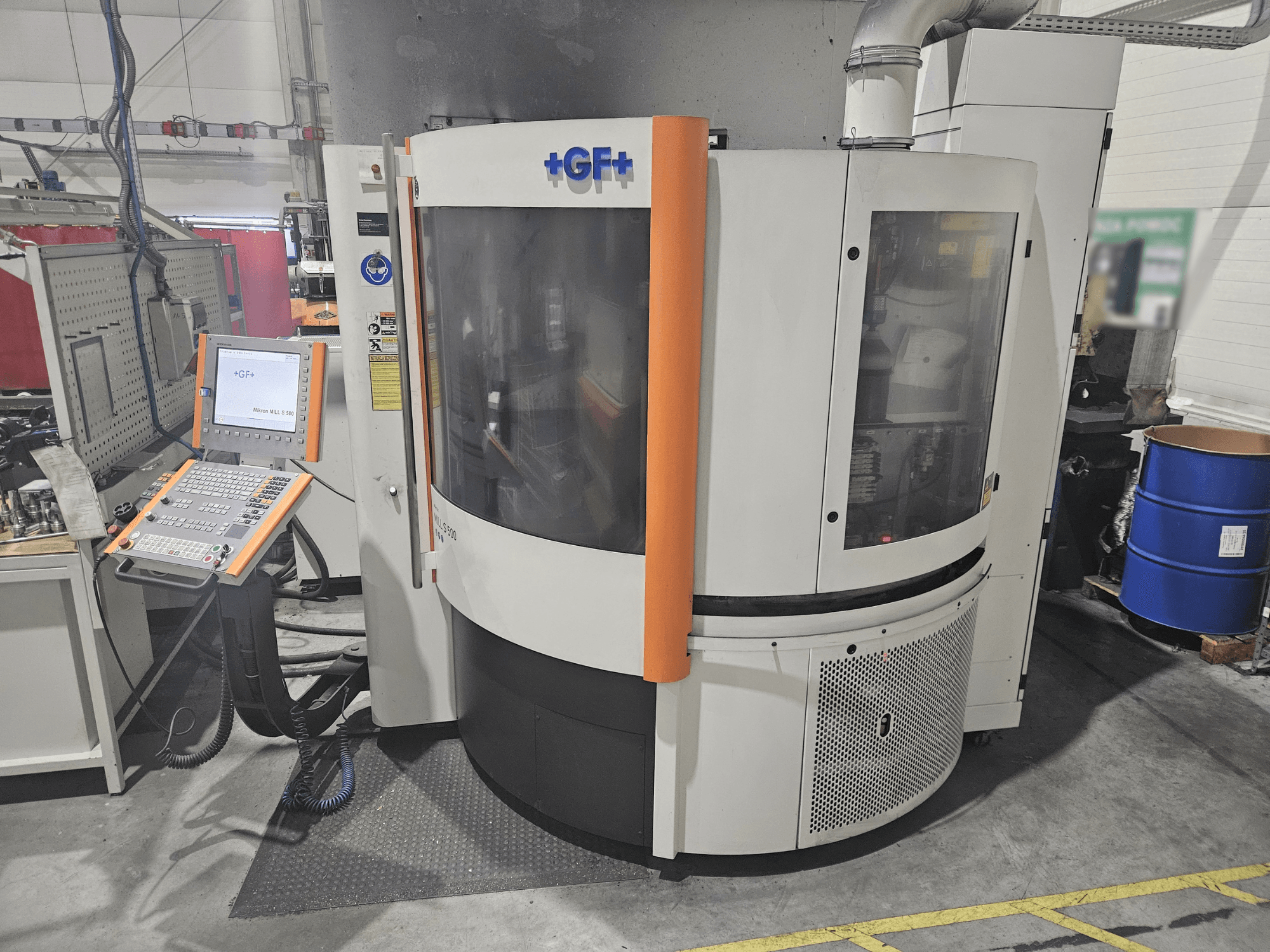 Máquina herramienta GF Machining Solutions con panel de control, vista frontal; presenta panel transparente, detalles en naranja y configuración industrial.