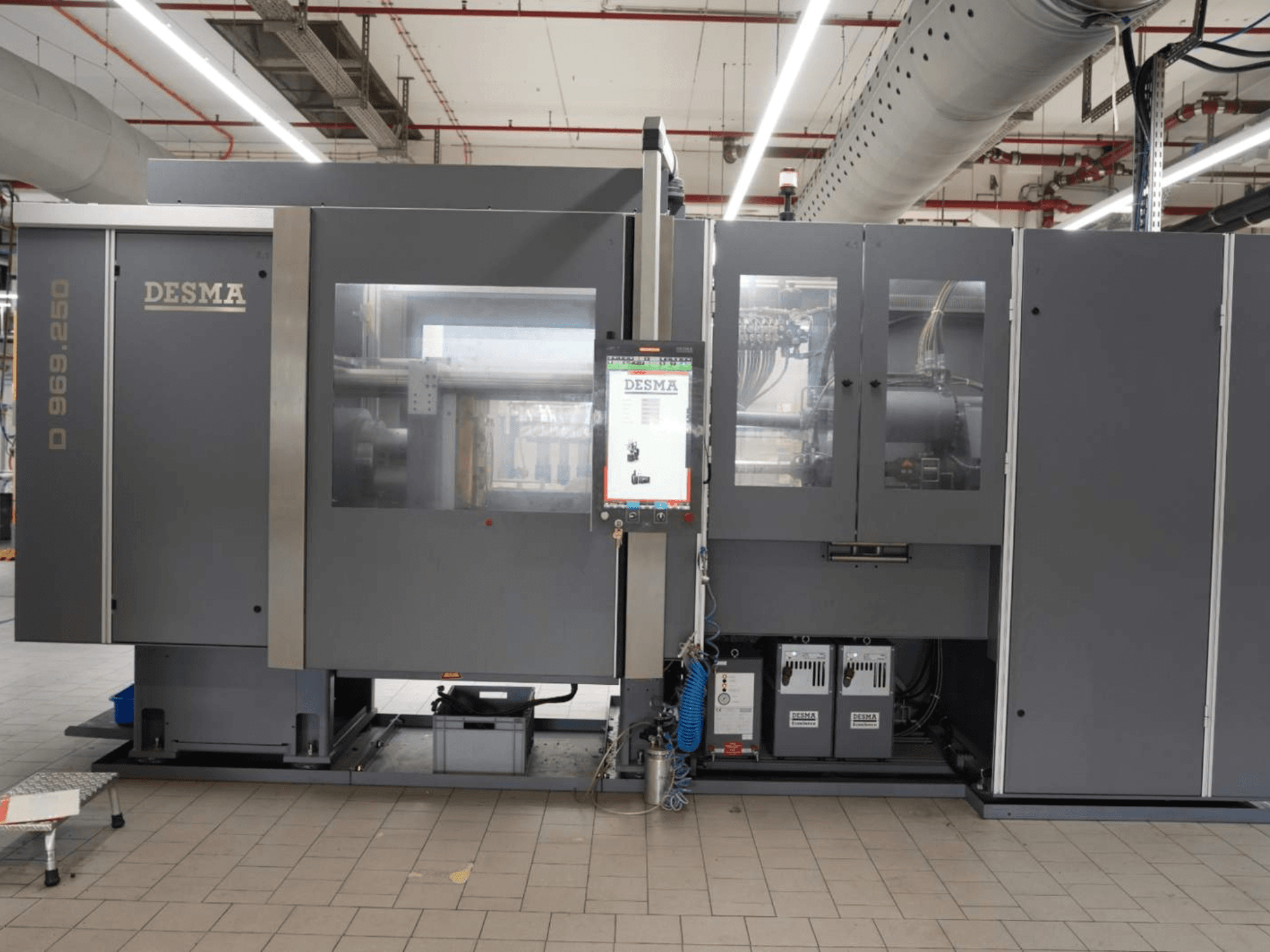Máquina de moldeo por inyección vertical Kloeckner Desma D 969.250 Z (S3) en un entorno industrial, vista frontal con panel de control.