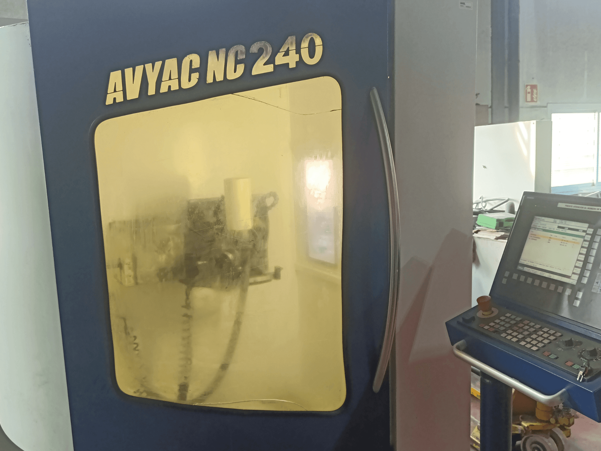 Rectificadora cilíndrica AVYAC NC240, vista lateral que muestra el panel de control y la zona de rectificado parcialmente visible a través de la ventana.