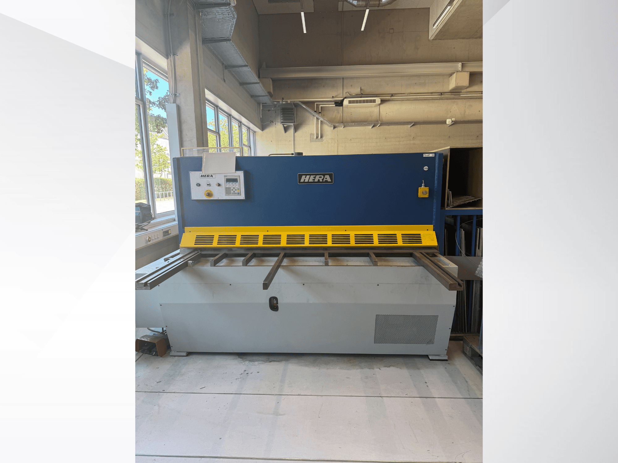 Cizalla hidráulica HERA TS 2000x6 vista de frente, con un diseño en azul y amarillo, que incluye el panel de control y la mesa de corte.