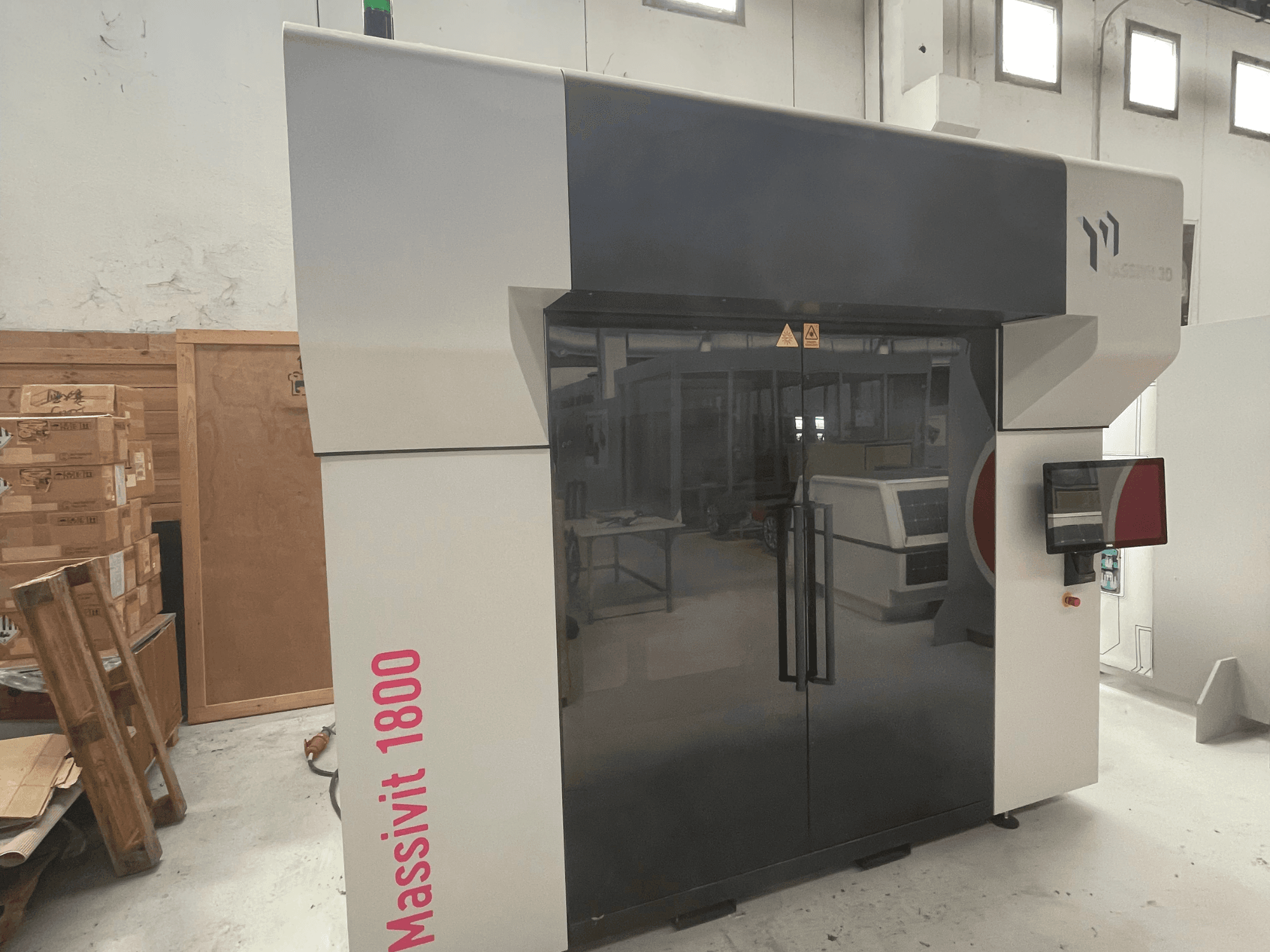 Impresora 3D de plástico MASSIVIT Massivit 1800, vista de perfil, con pantalla táctil y un elegante diseño en blanco y negro.