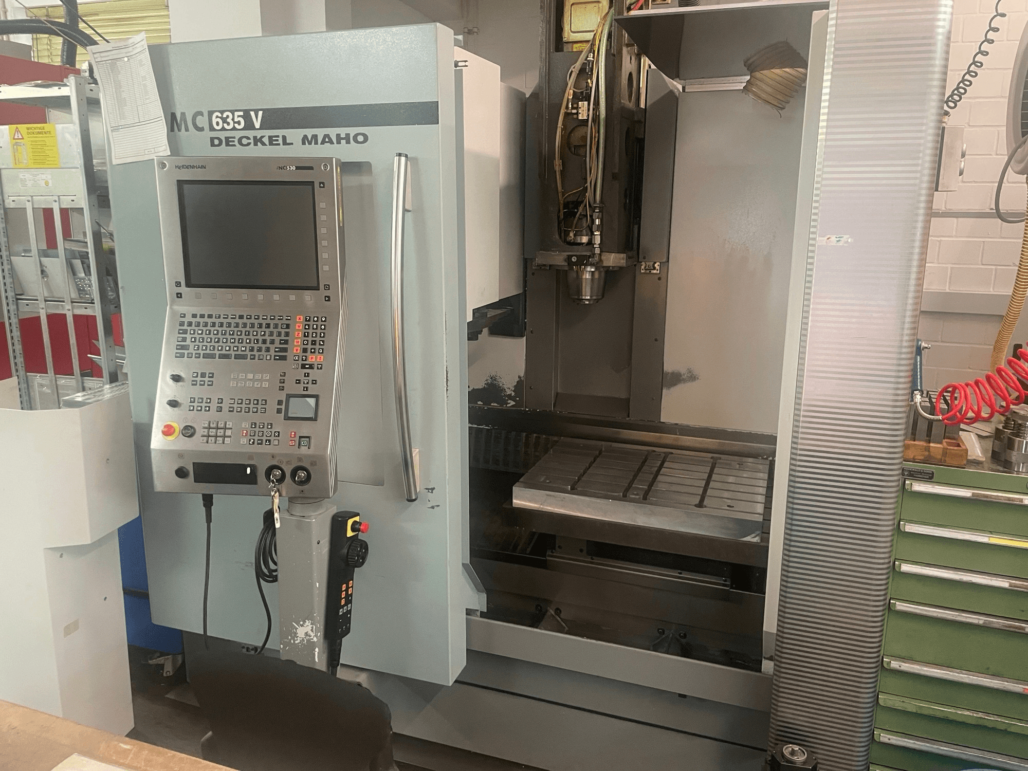 Vista frontal del centro de mecanizado vertical DECKEL MAHO DMC 635 V con el panel de control y la zona de trabajo abierta, en la que se aprecian el cabezal portaherramientas y la bancada.