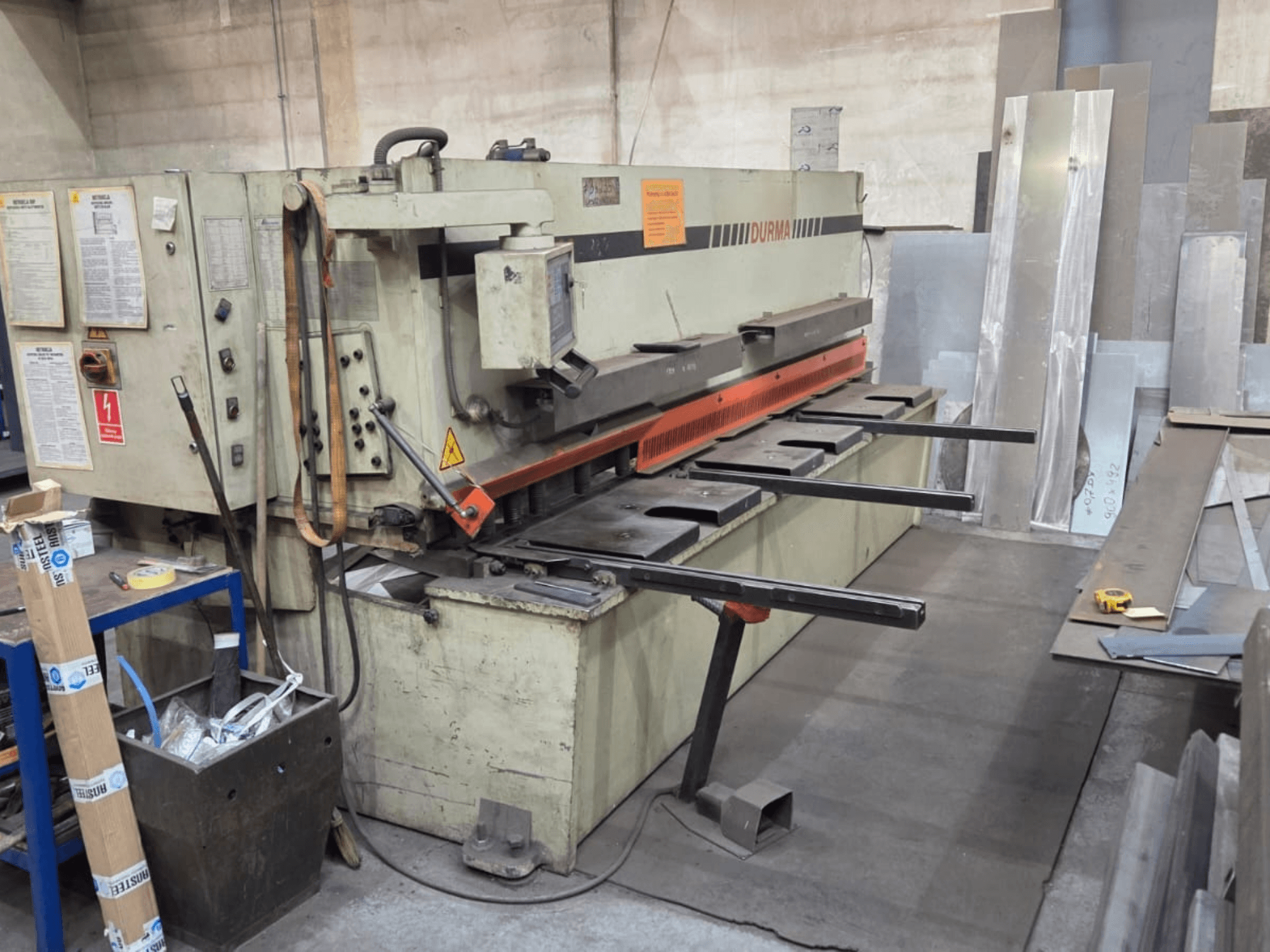 Cizalla hidráulica Durma SB 3060, vista frontal, mostrando controles, cuchilla de corte y chapas metálicas en el espacio de trabajo.