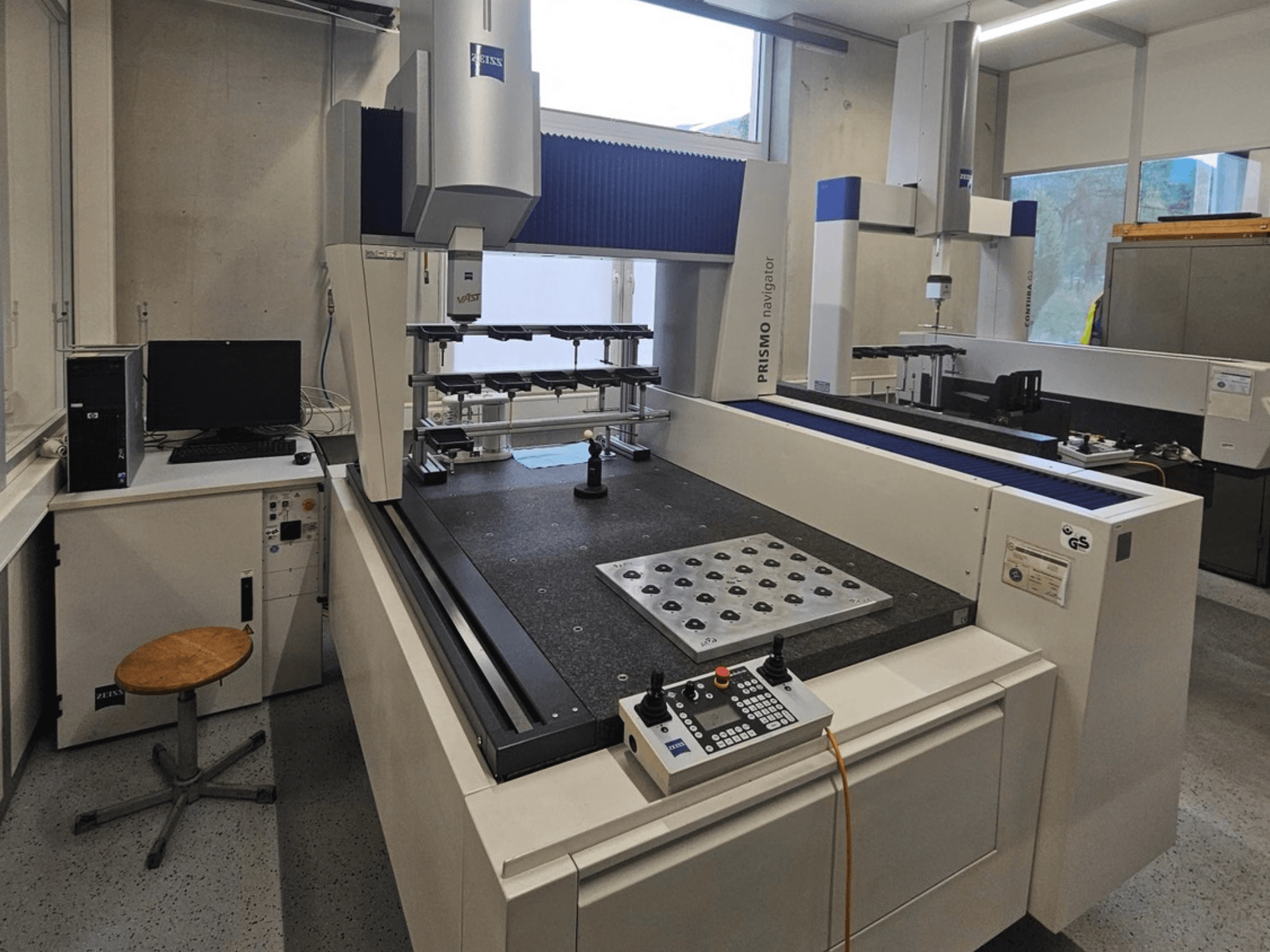 Máquina de medición por coordenadas (CMM) ZEISS Prismo Navigator 7 en un laboratorio; vista frontal en la que se aprecian el panel de control, la mesa de trabajo y el monitor.