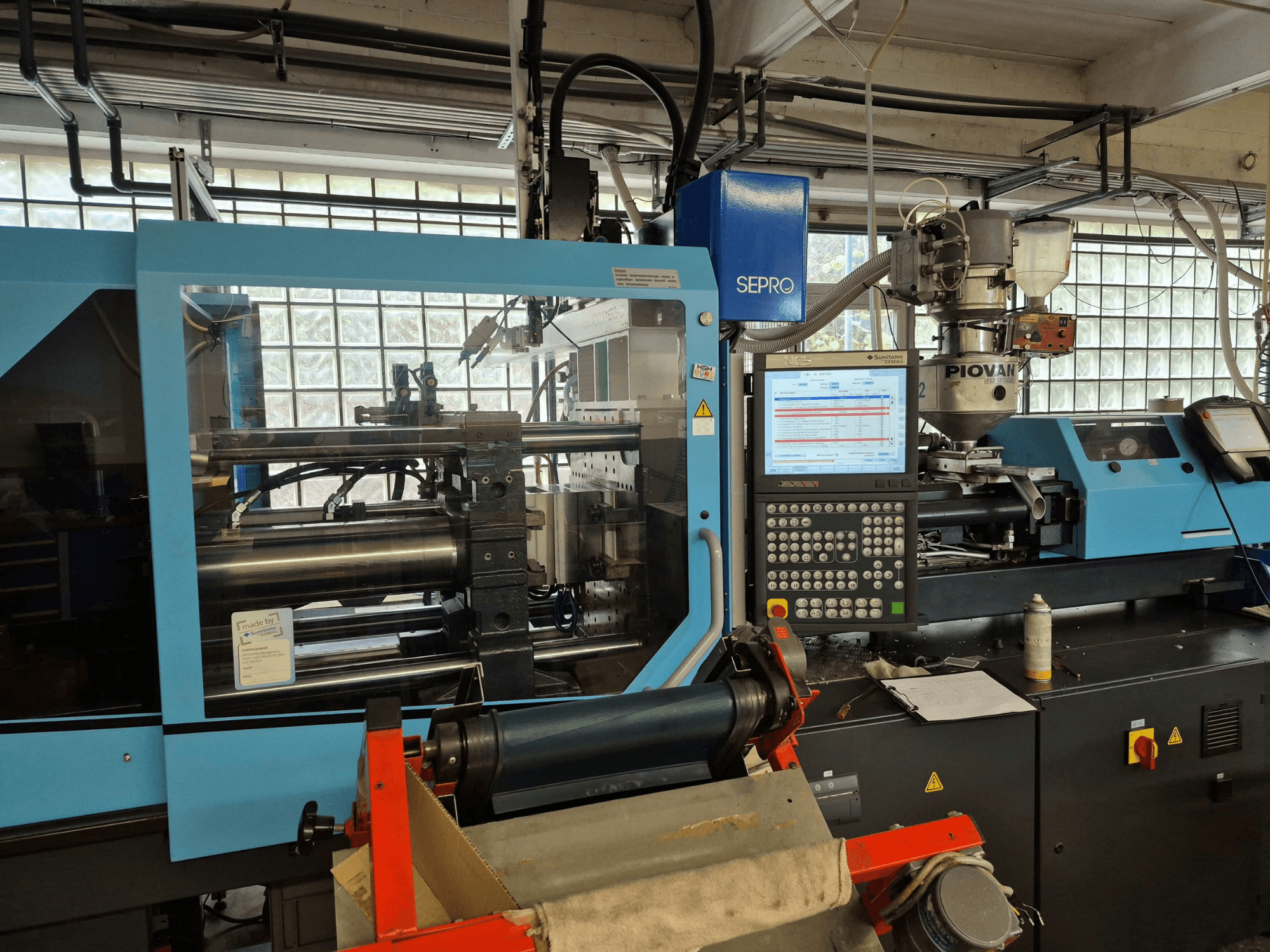 Máquina de moldeo por inyección hidráulica SUMITOMO SHI DEMAG Systec 120/470-430, vista frontal en la que se aprecian el panel de control y el sistema de alimentación.