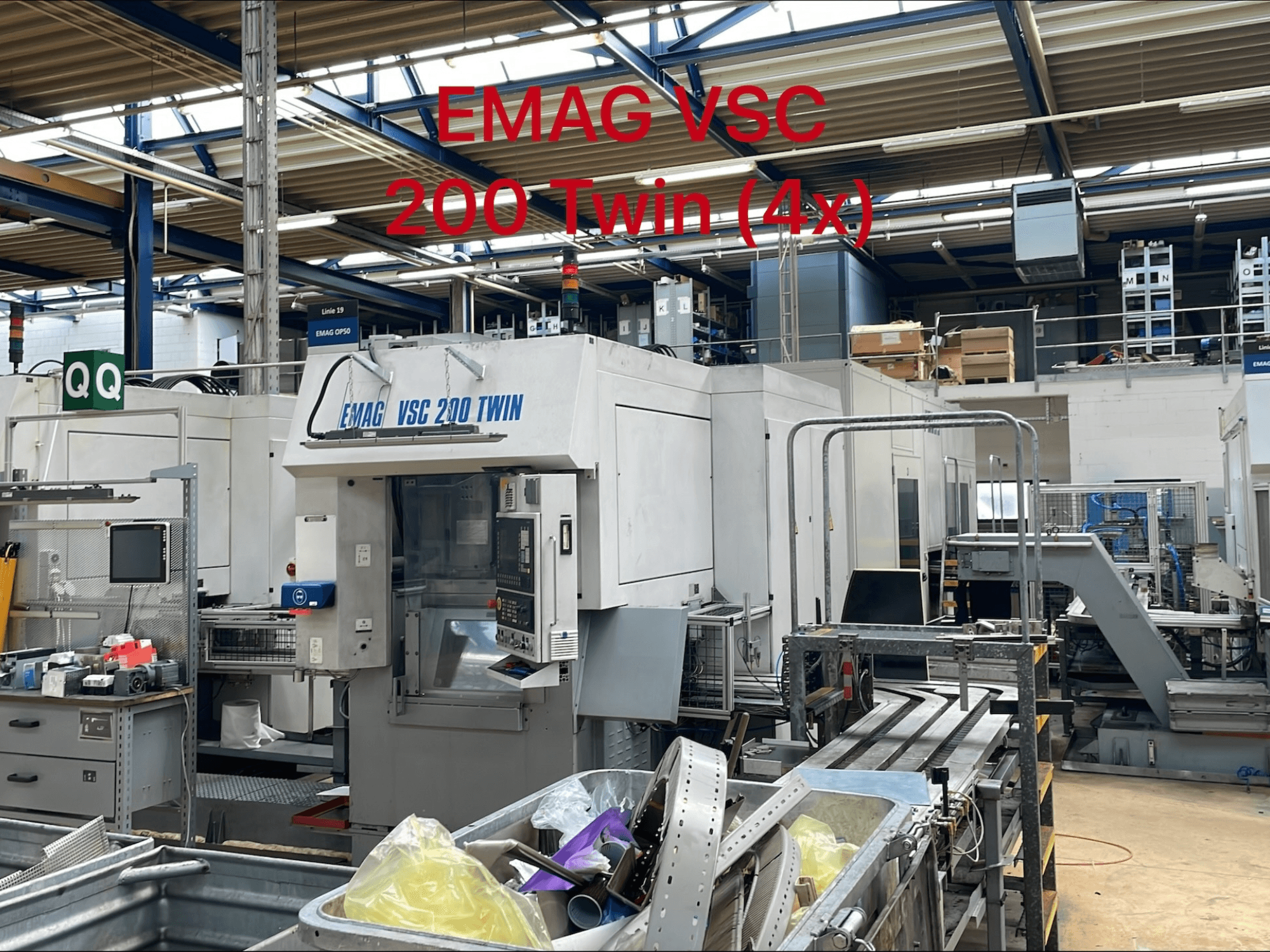 Máquina de torneado vertical EMAG VSC 200 TWIN en un entorno de fábrica, vista frontal mostrando los controles y el área de almacenamiento de herramientas.