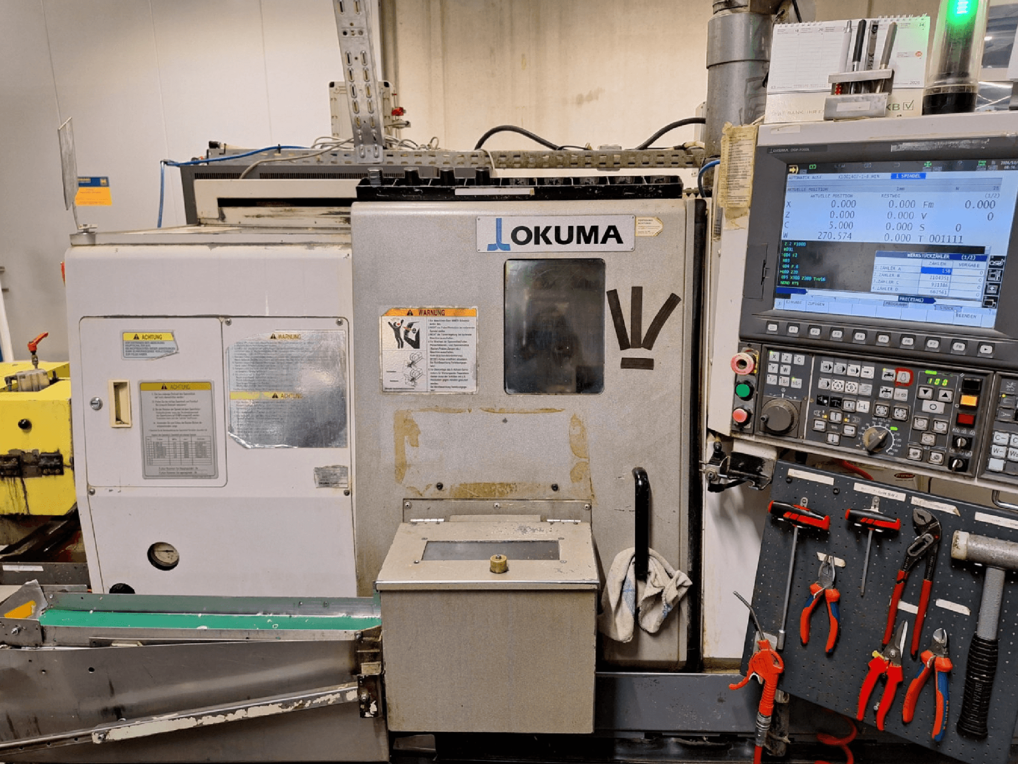 Torno horizontal Okuma LB200-MW, vista frontal, con el panel de control y las herramientas visibles en el lateral.