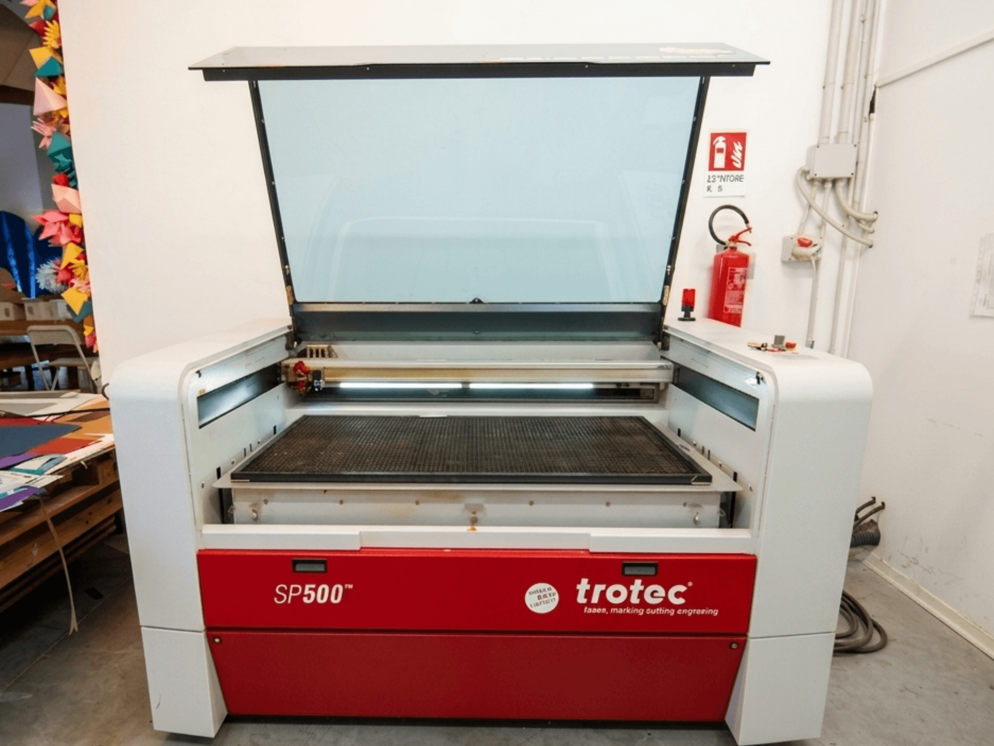 Máquina de grabado láser Trotec SP500 C200 en vista frontal, con una tapa abierta que muestra el área de trabajo y los controles.