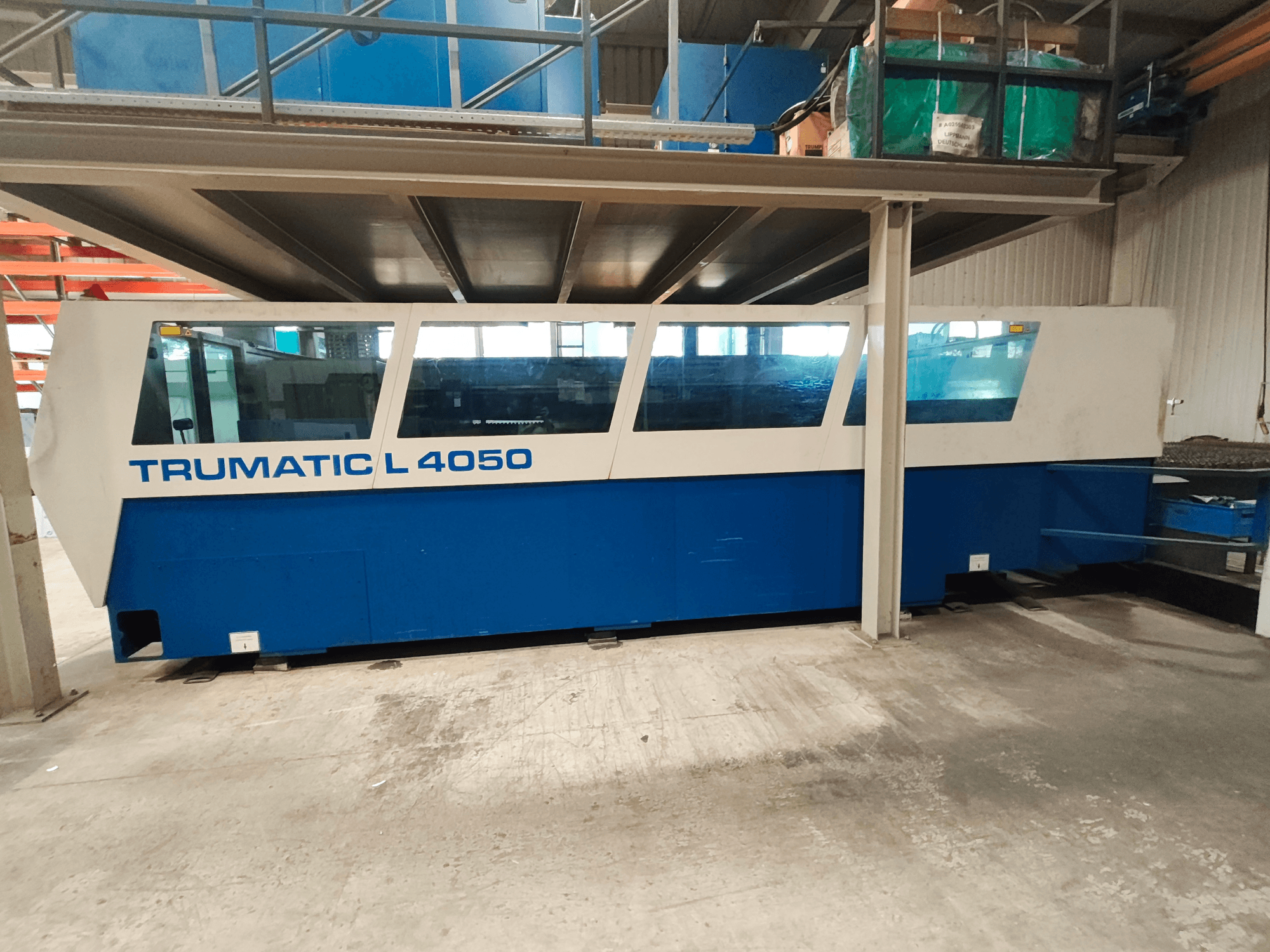 Máquina de corte por láser de CO₂ TRUMPF TruLaser 450 vista de perfil, con un diseño en azul y blanco, en la que se aprecian el panel de control y el espacio de trabajo.