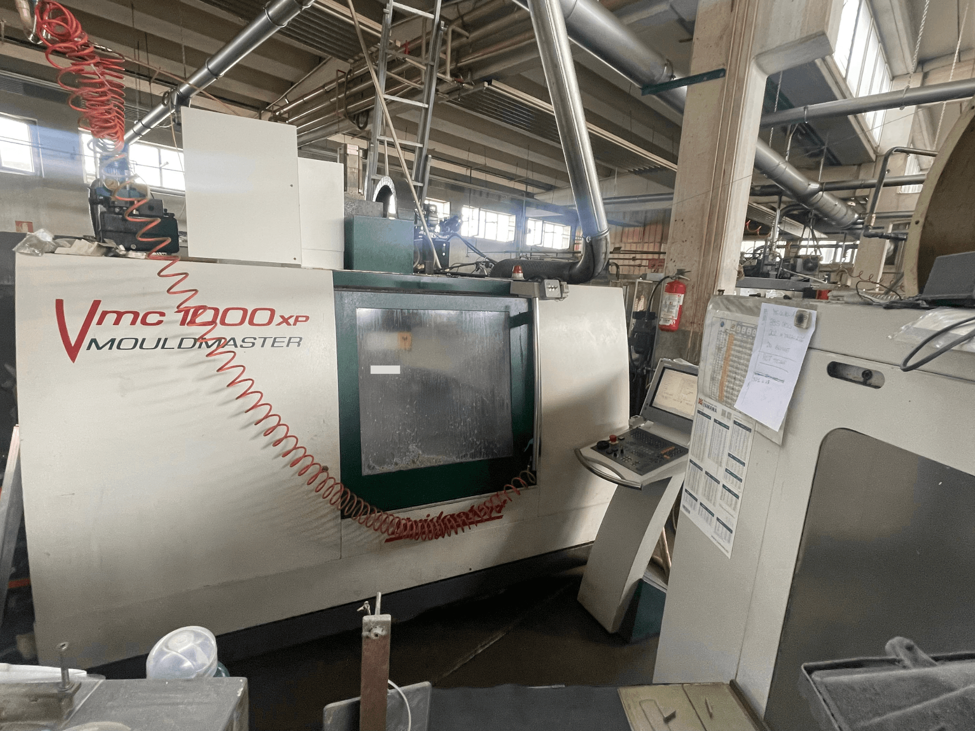 Centro de mecanizado vertical Bridgeport VMC 1000, vista frontal, en la que se aprecian el panel de control y los detalles de la máquina en un entorno industrial.