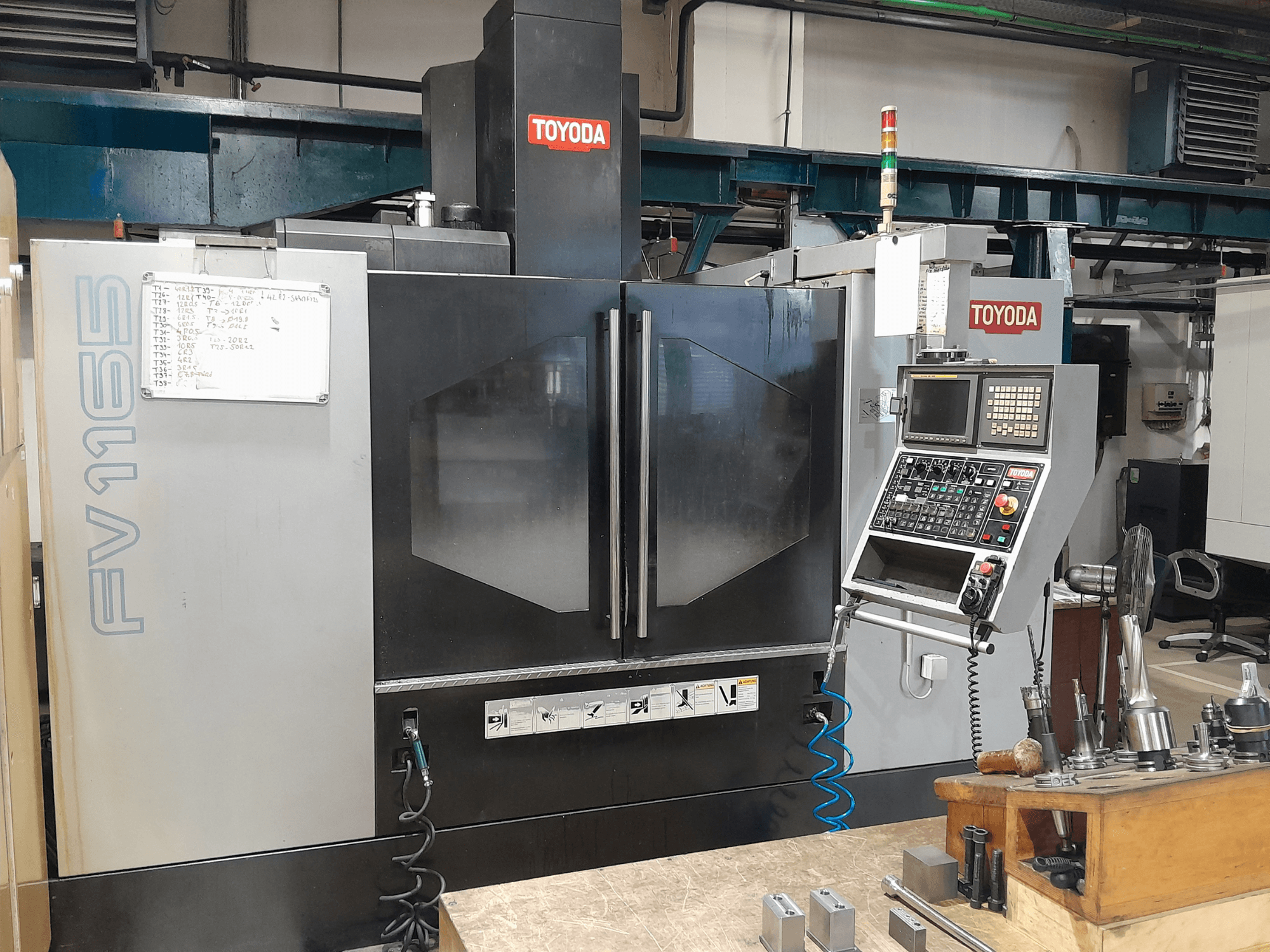Centro de mecanizado vertical TOYODA FV 1165, vista frontal, mostrando el panel de control y los indicadores de funcionamiento.