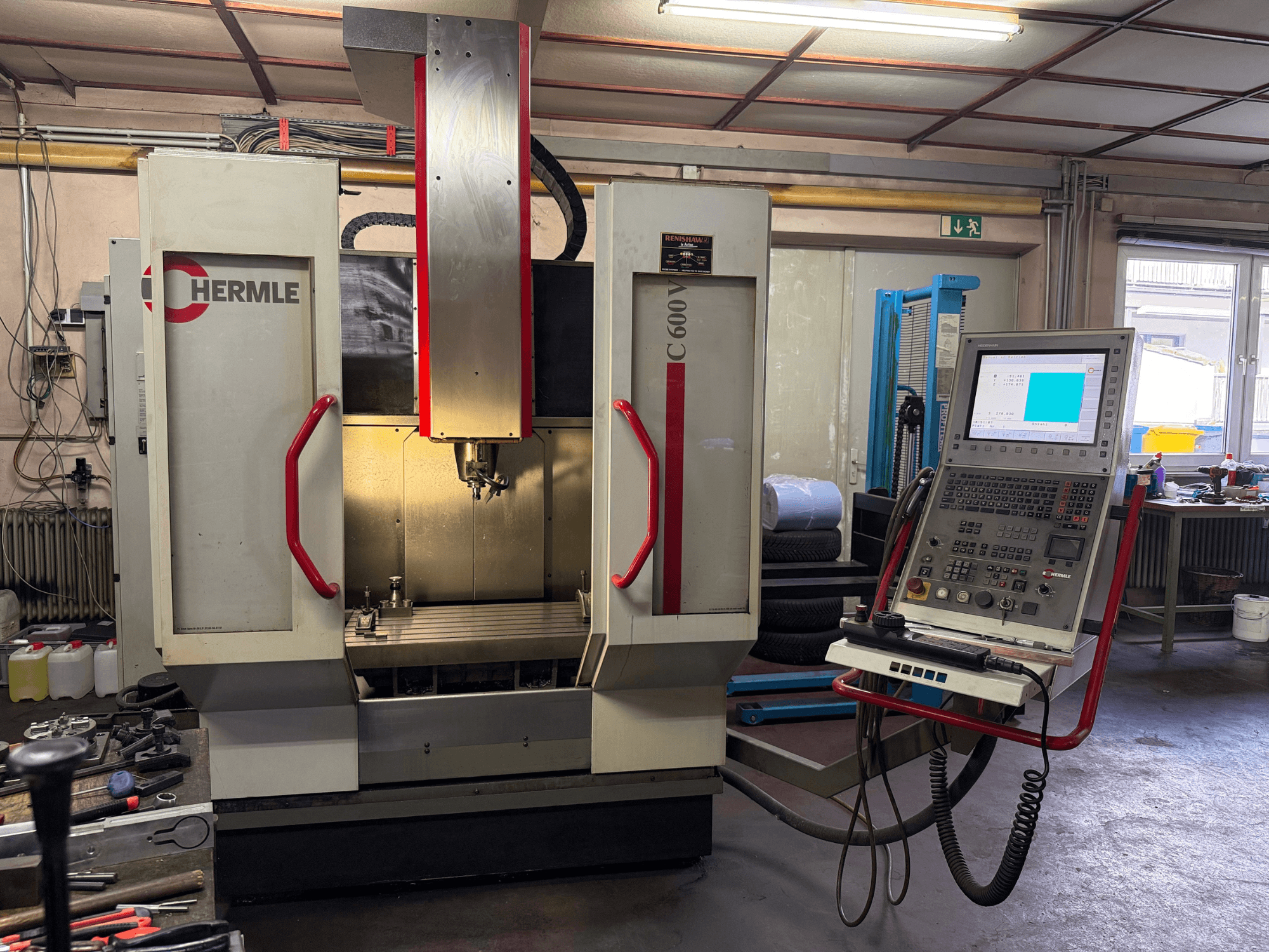 Fresadora CNC Hermle C 600 desde una vista frontal, con un panel de control con numerosos botones y una amplia zona de trabajo.