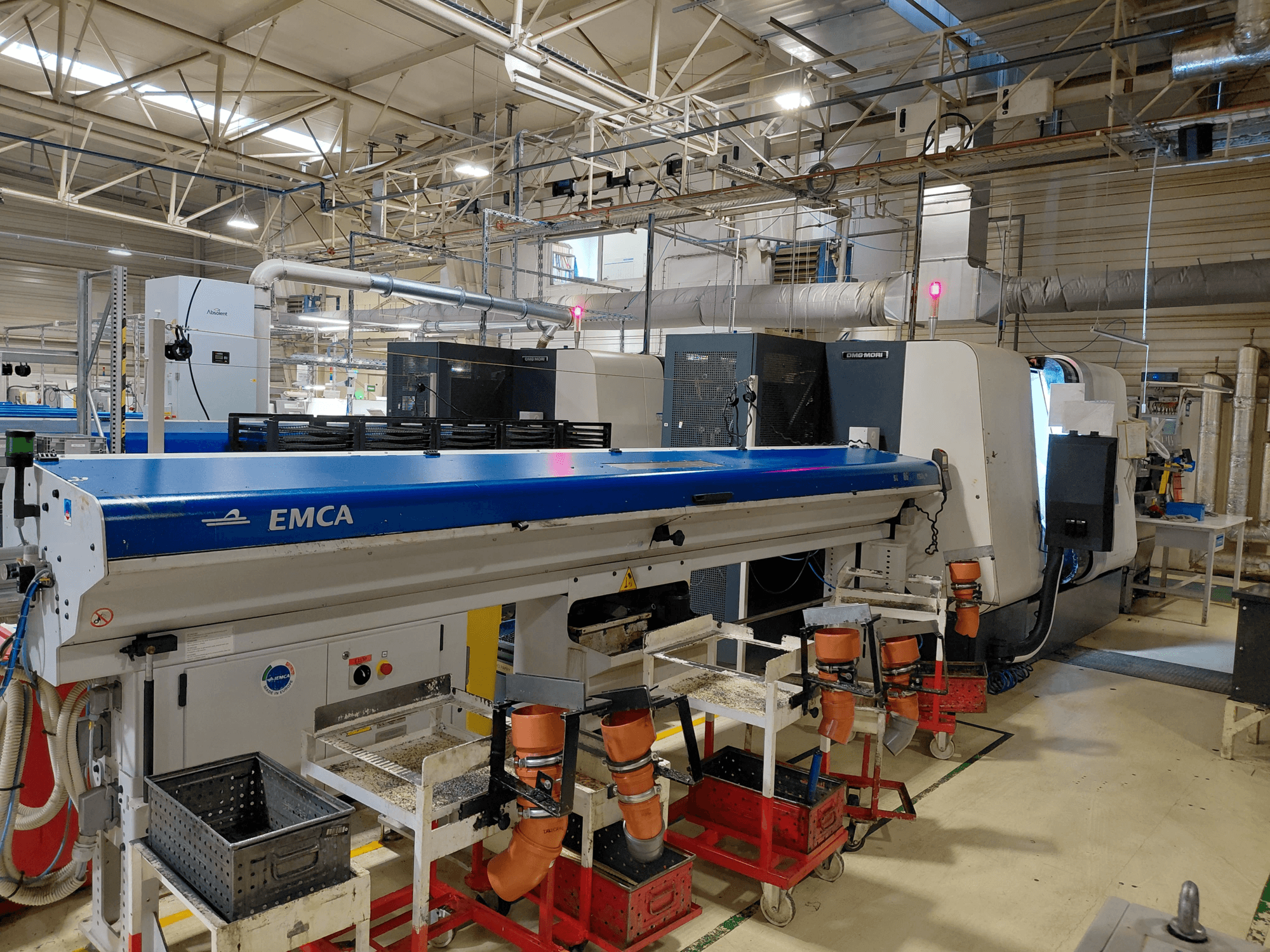 Máquina de torneado multihusillo DMG MORI Sprint 65 linear en un taller, vista lateral mostrando la automatización EMCA y la configuración de las herramientas.