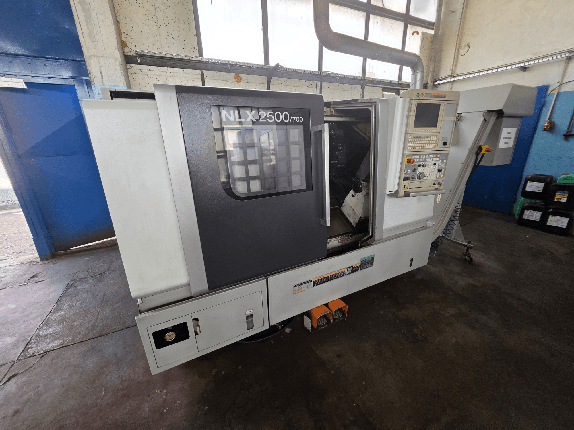 Torno horizontal DMG MORI NLX 2500/700 en vista lateral, en el que se aprecian el panel de control y la zona de mecanizado.