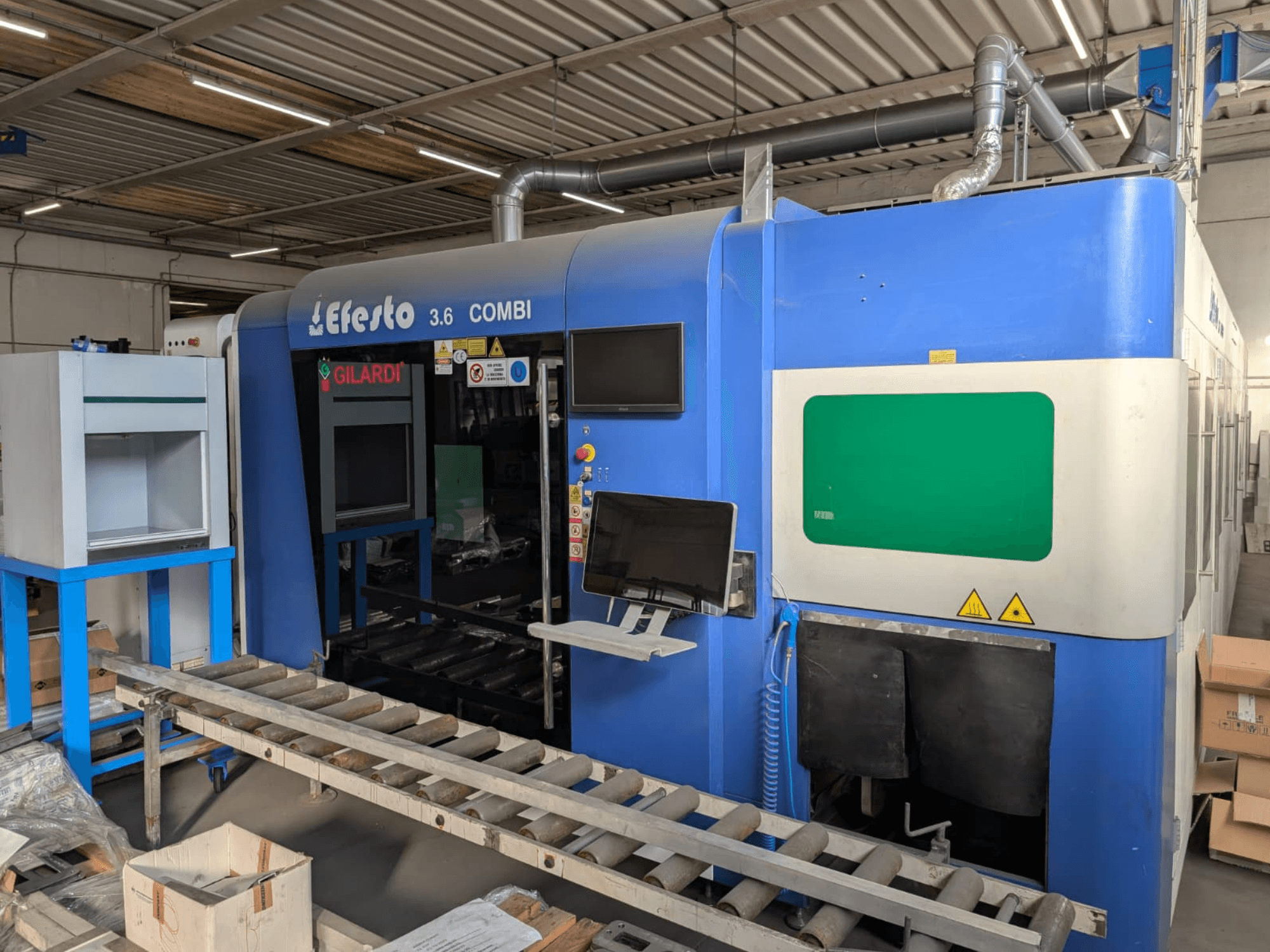Máquina de corte por láser de fibra EFESTO 3.6 COMBI, vista lateral, con panel de control e indicadores de seguridad y acabado exterior en azul.