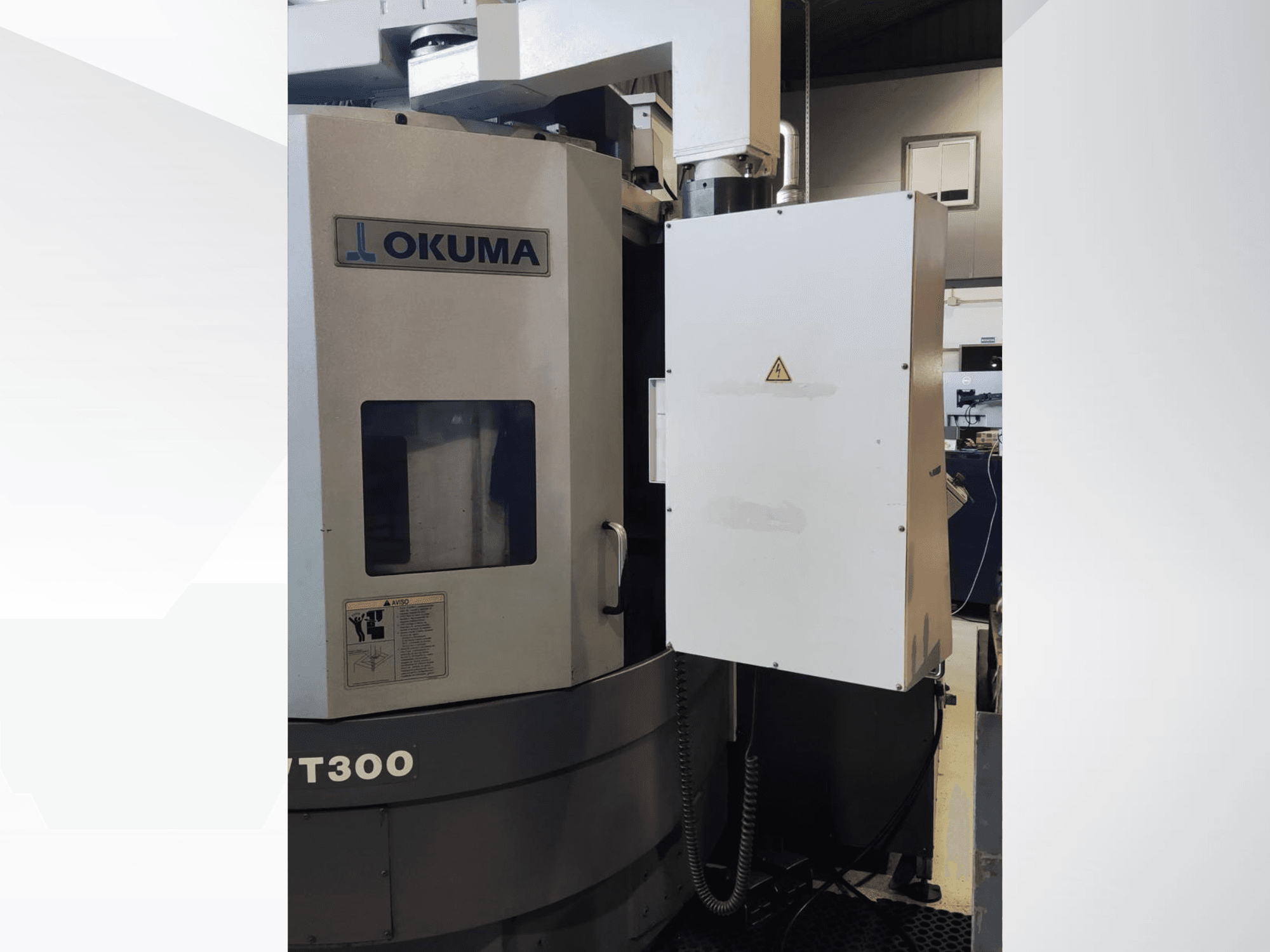 Máquina de torneado vertical Okuma LVT300, vista frontal, mostrando el panel de control y las características de seguridad etiquetadas.