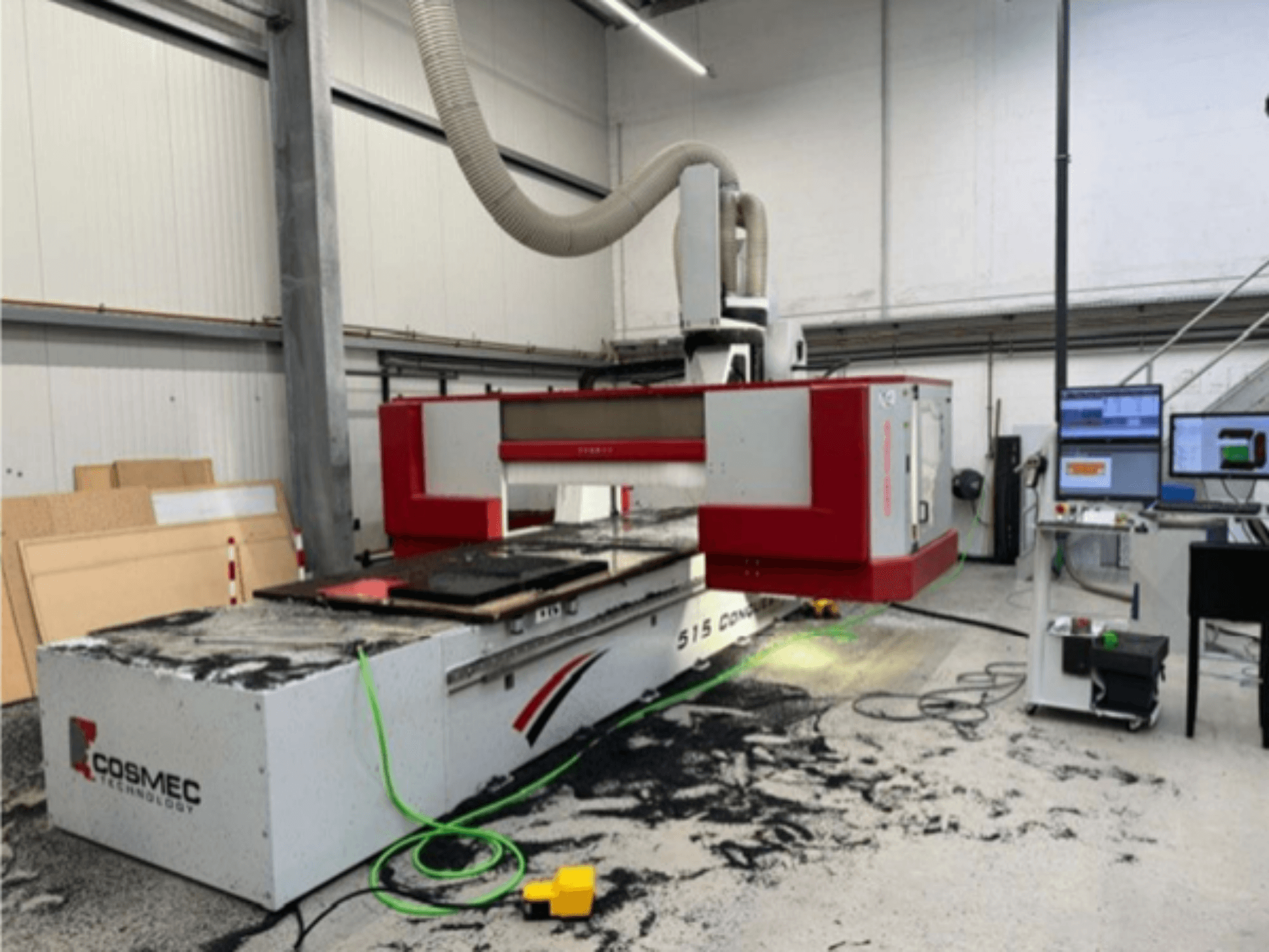 Máquina CNC Cosmec 515 en taller con un terminal de ordenador, mostrando una vista frontal y polvo esparcido por la superficie.