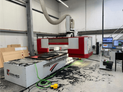 Máquina CNC Cosmec 515 en taller con un terminal de ordenador, mostrando una vista frontal y polvo esparcido por la superficie.