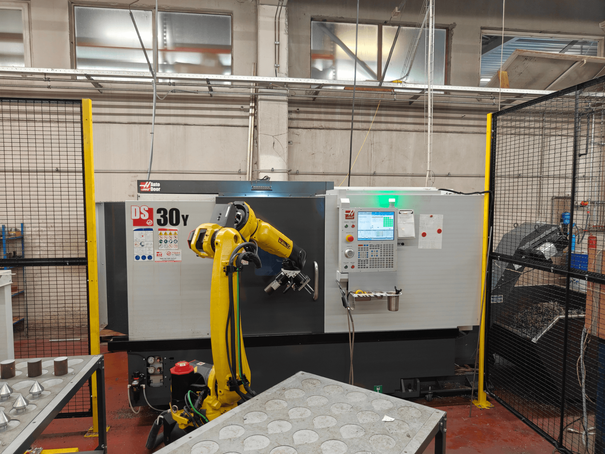 Torno horizontal HAAS DS30Y con brazo robótico, vista frontal, en la que se aprecian el panel de control y el espacio de trabajo.