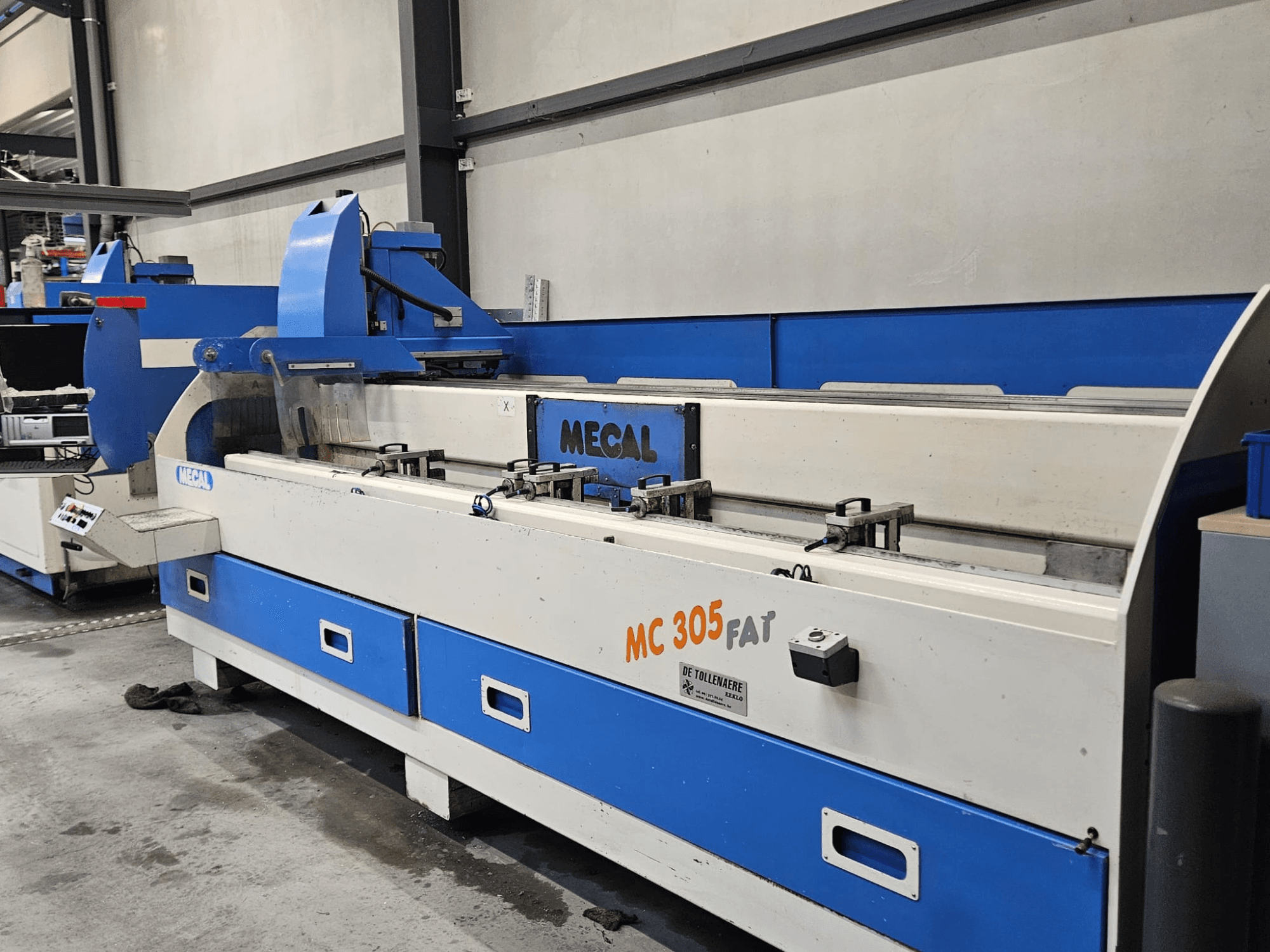 Máquina MECAL MC 305 FAT en un entorno de fábrica, vista frontal mostrando los controles y el diseño azul y blanco.