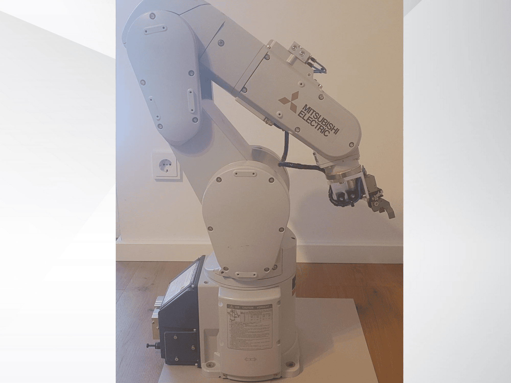 Brazo robótico Mitsubishi Electric, vista lateral, con pinza y panel de control detallado en la base para los ajustes de funcionamiento.