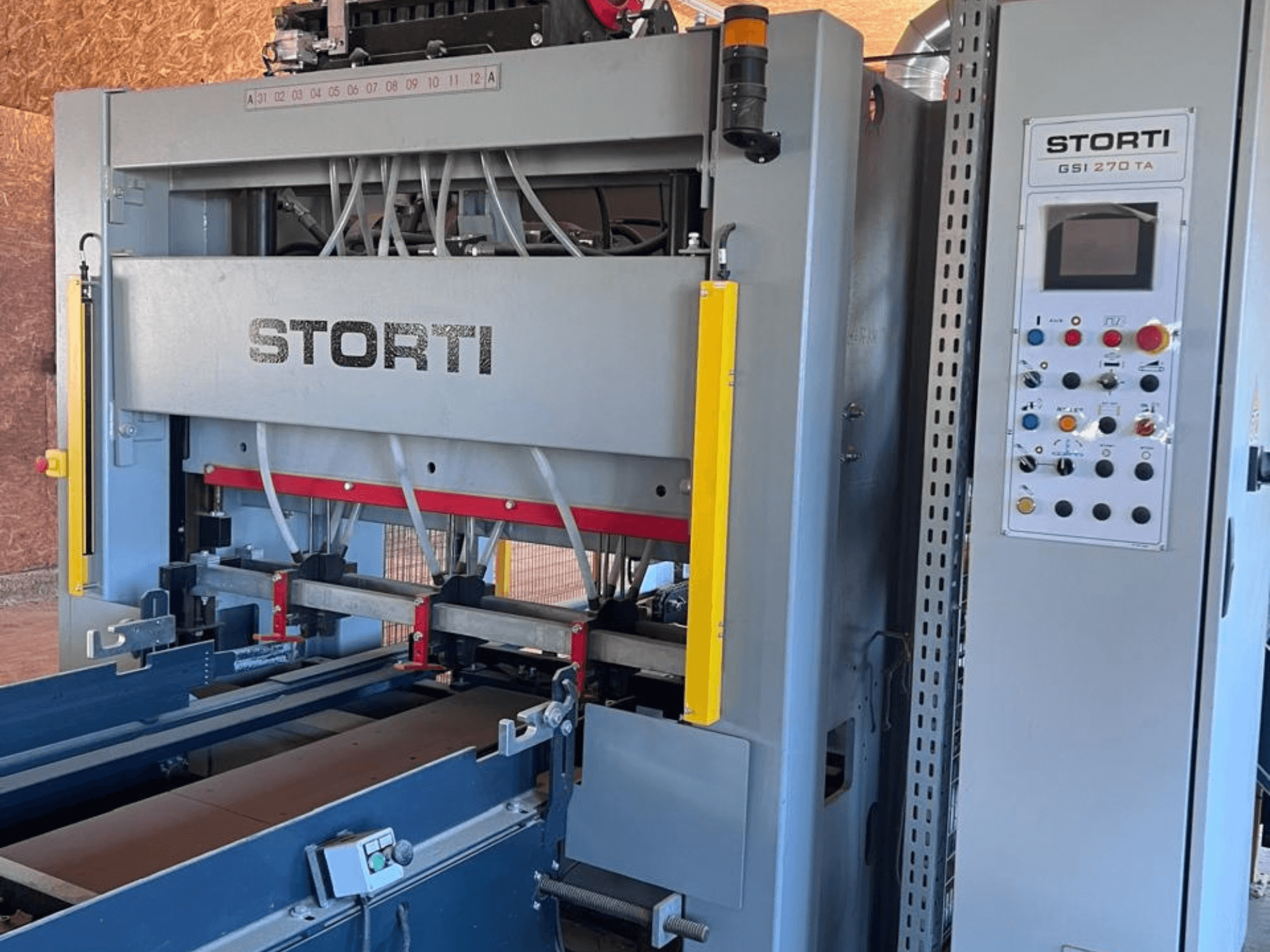 Línea de producción de madera STORTI GSI 170-270 TA9, vista frontal en la que se aprecian el panel de control y los mecanismos de la prensa hidráulica.